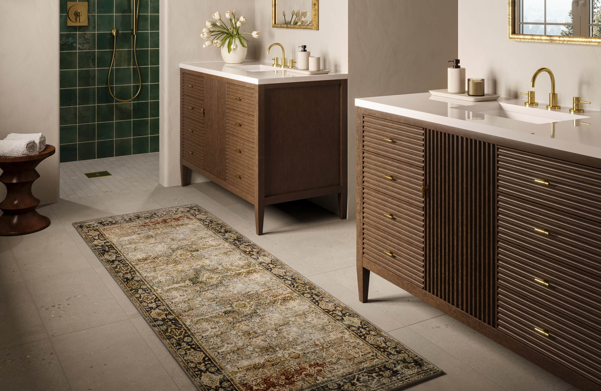 Modern bathroom with light terrazzo floor tiles, wood double vanities, and brass fixtures paired with deep green shower wall tiles.