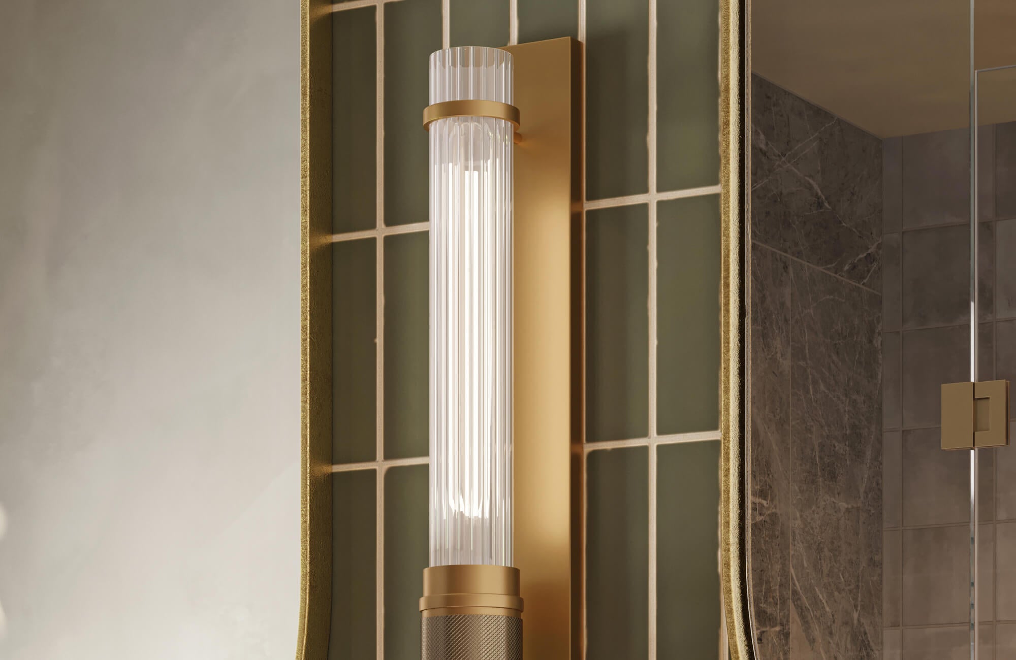 Modern brass wall light with a cylindrical glass shade, adding soft illumination to a bathroom with green tile detail.