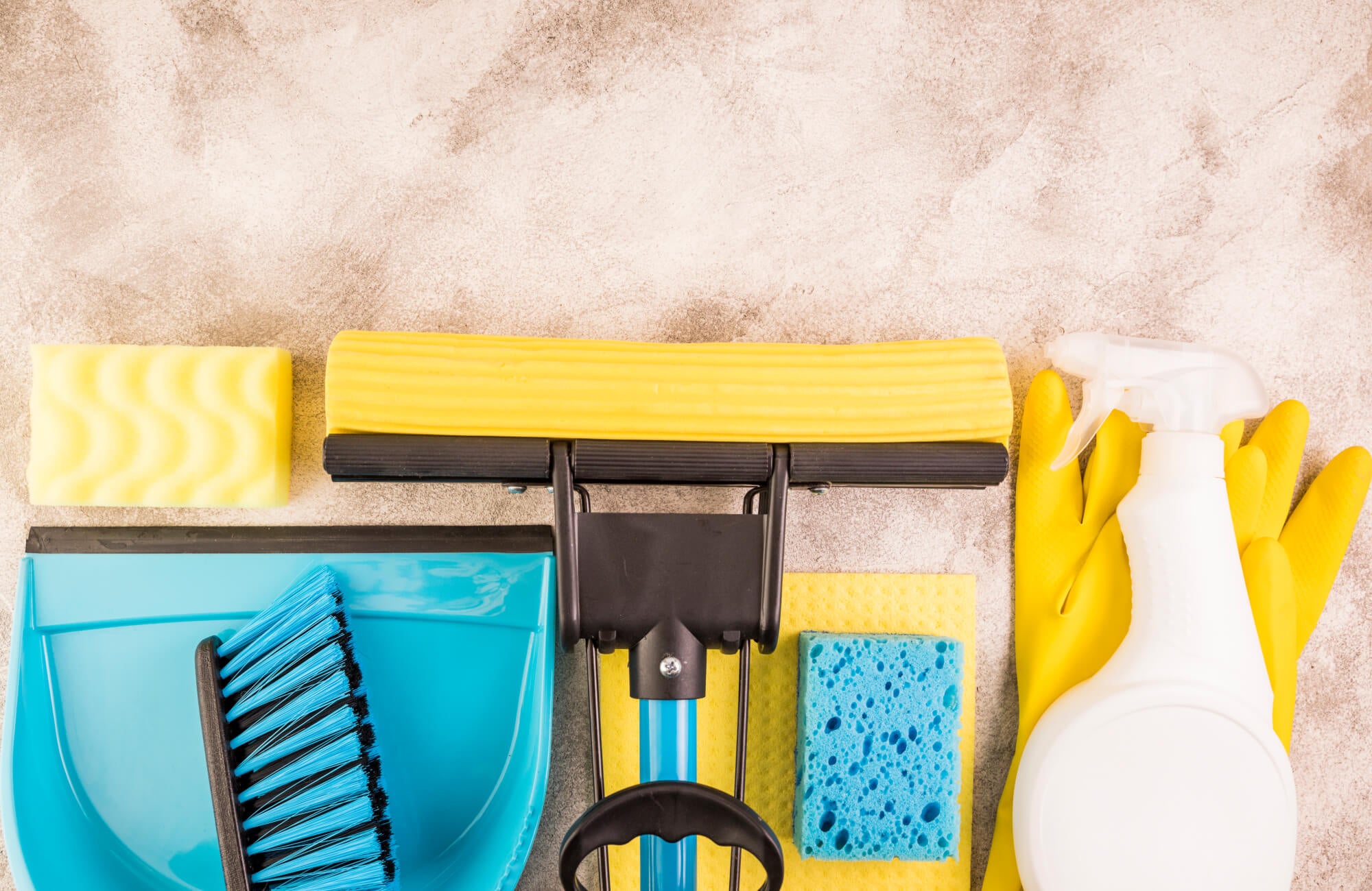 Set of cleaning tools including sponge, gloves, spray bottle, and dustpan, arranged on a stone-textured background.