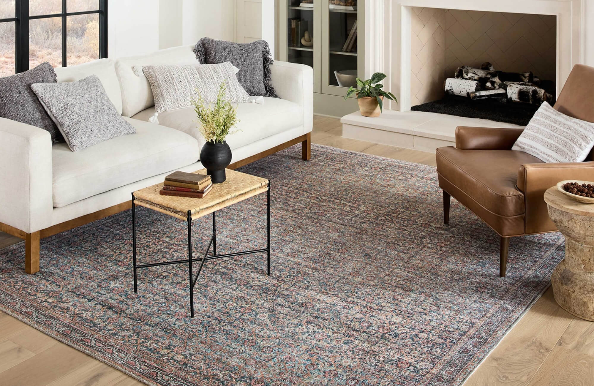 null Elegant living room featuring a vintage-inspired area rug in muted blues and reds, grounded by neutral furniture and warm wood tones.