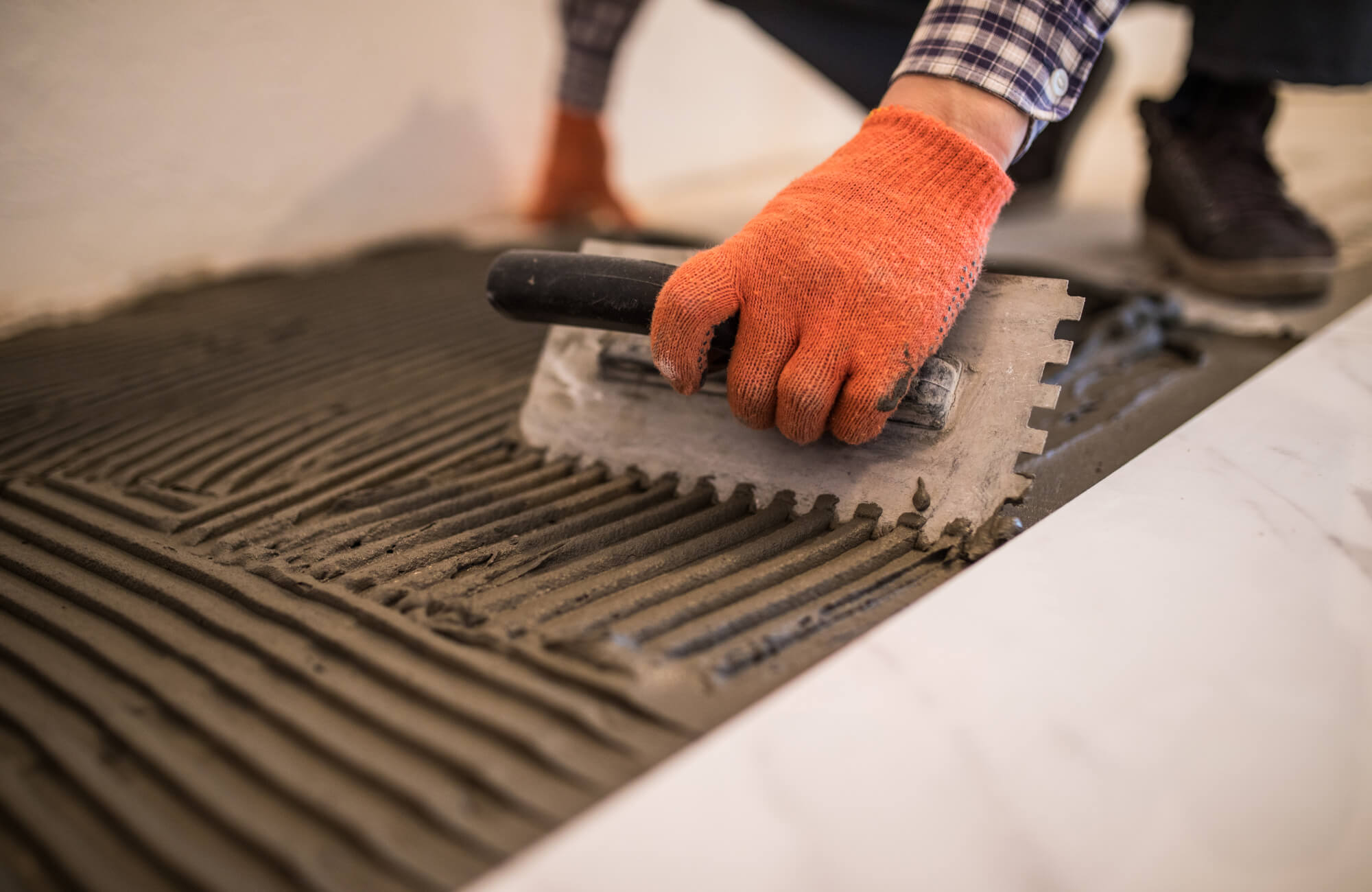 null Close-up of mortar being spread with a notched trowel during marble look tile installation.