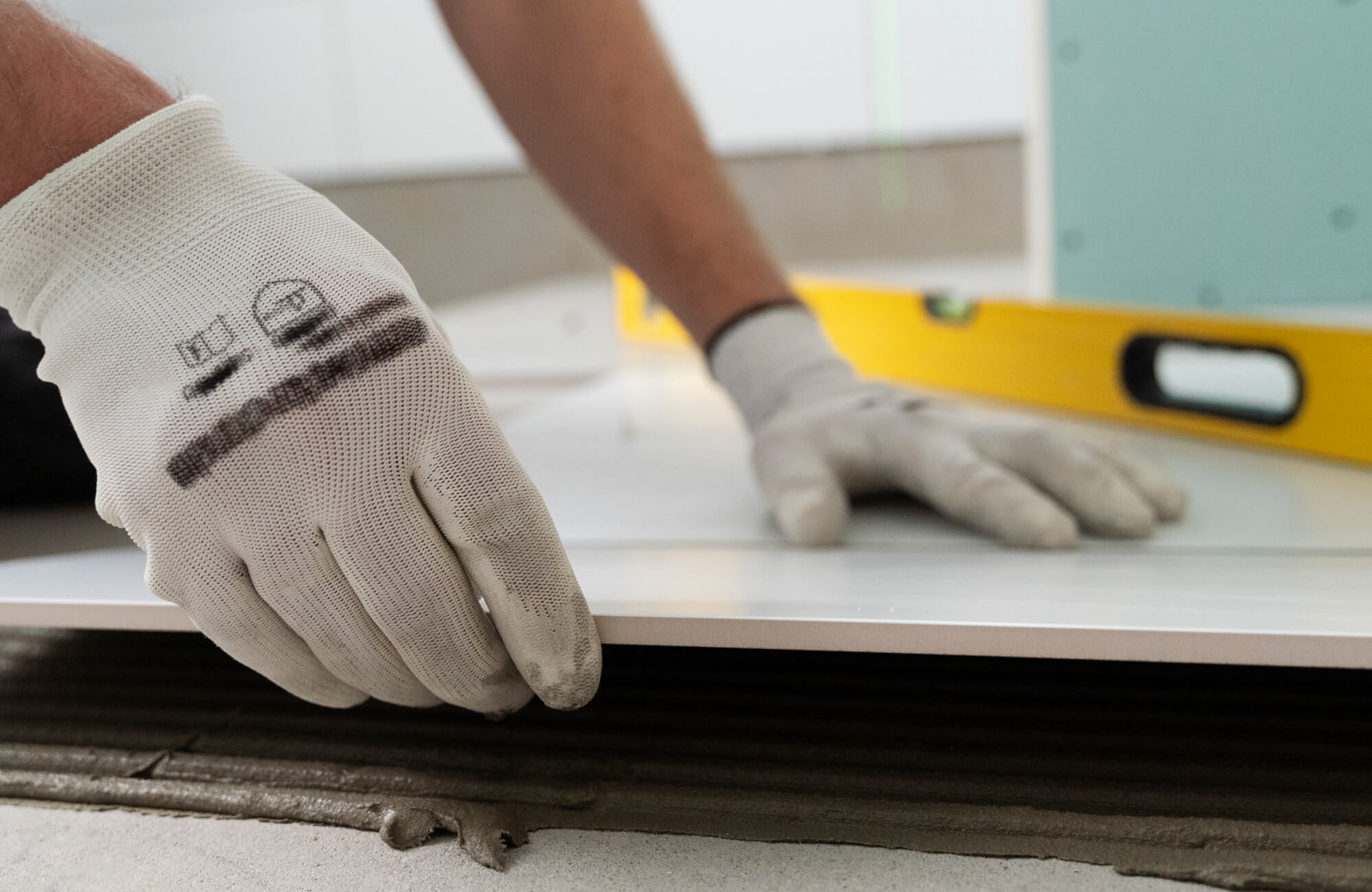 null Installer placing a marble look tile over freshly spread mortar with a level in the background.