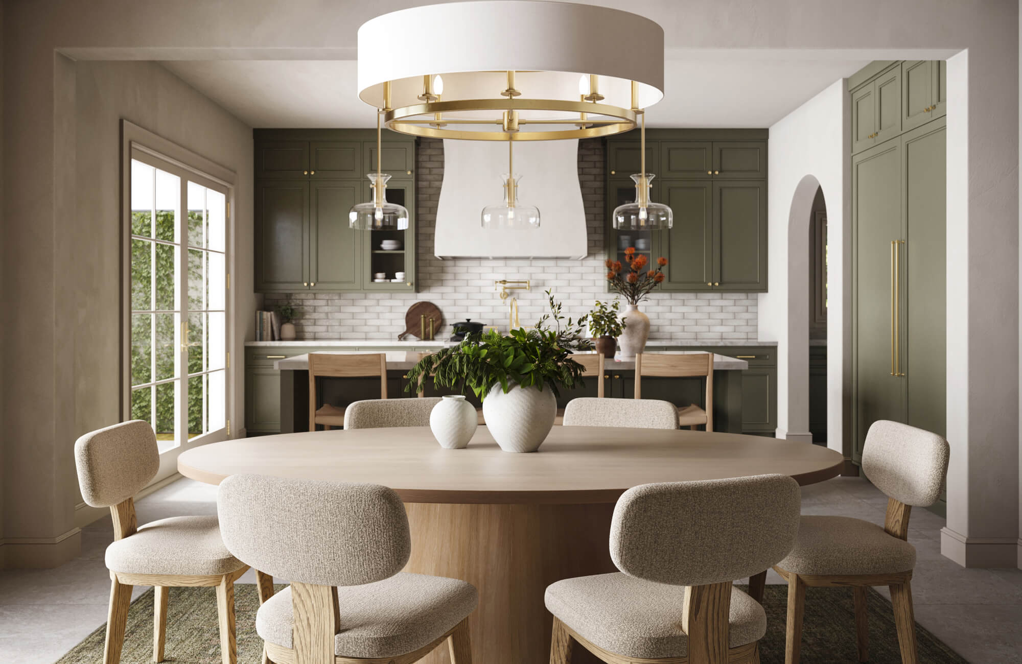 A modern dining space featuring a circular table lit by a statement chandelier, with additional pendant and task lighting extending into the kitchen for cohesive illumination.