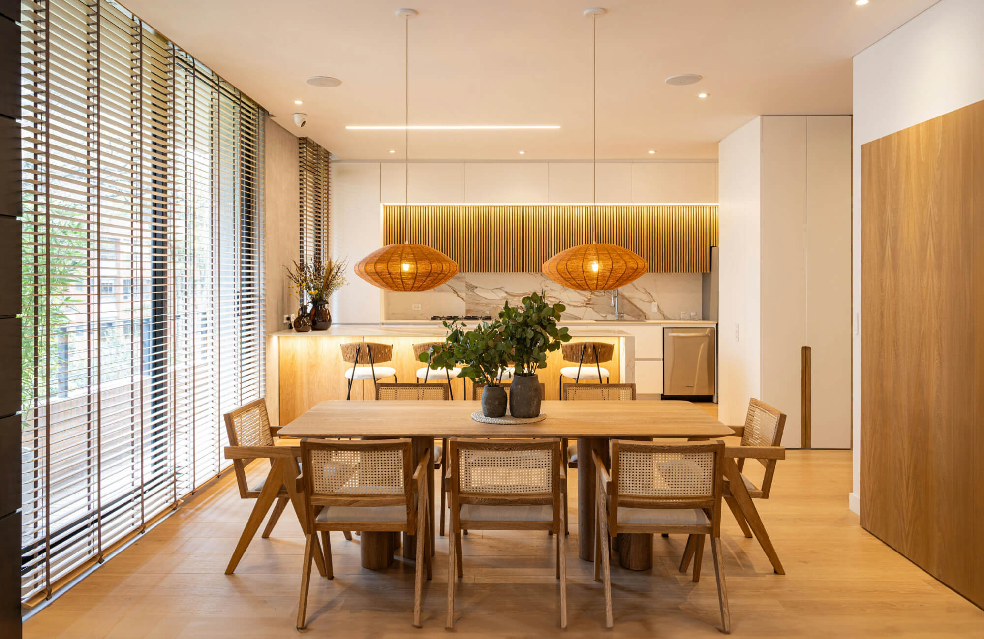 A contemporary dining area styled with textured pendant lights, recessed ceiling lights, and subtle accent lighting that creates a warm, cohesive atmosphere.