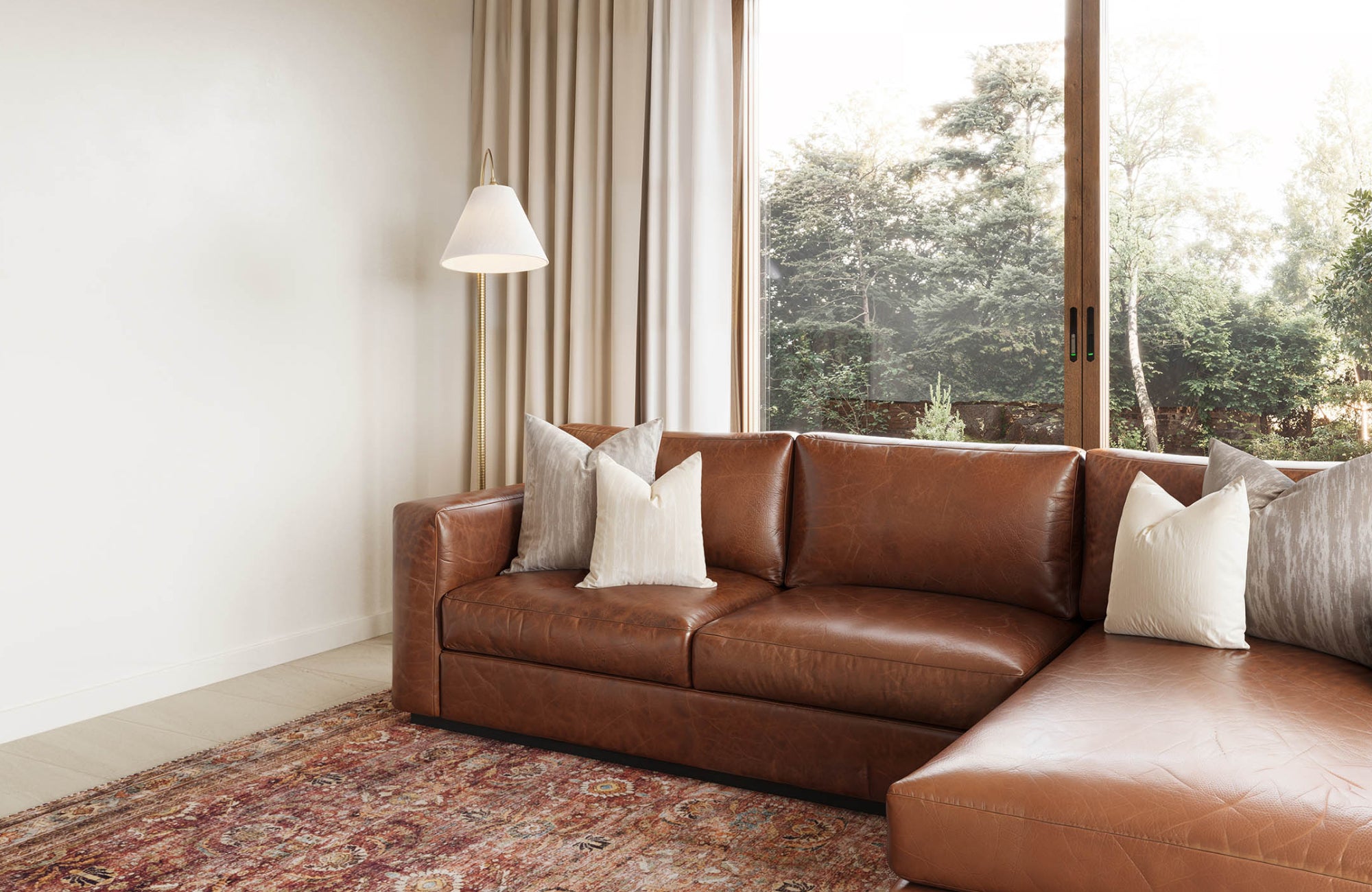 Warm-toned leather sofa next to a tall floor lamp, offering targeted lighting without relying on a ceiling fixture.