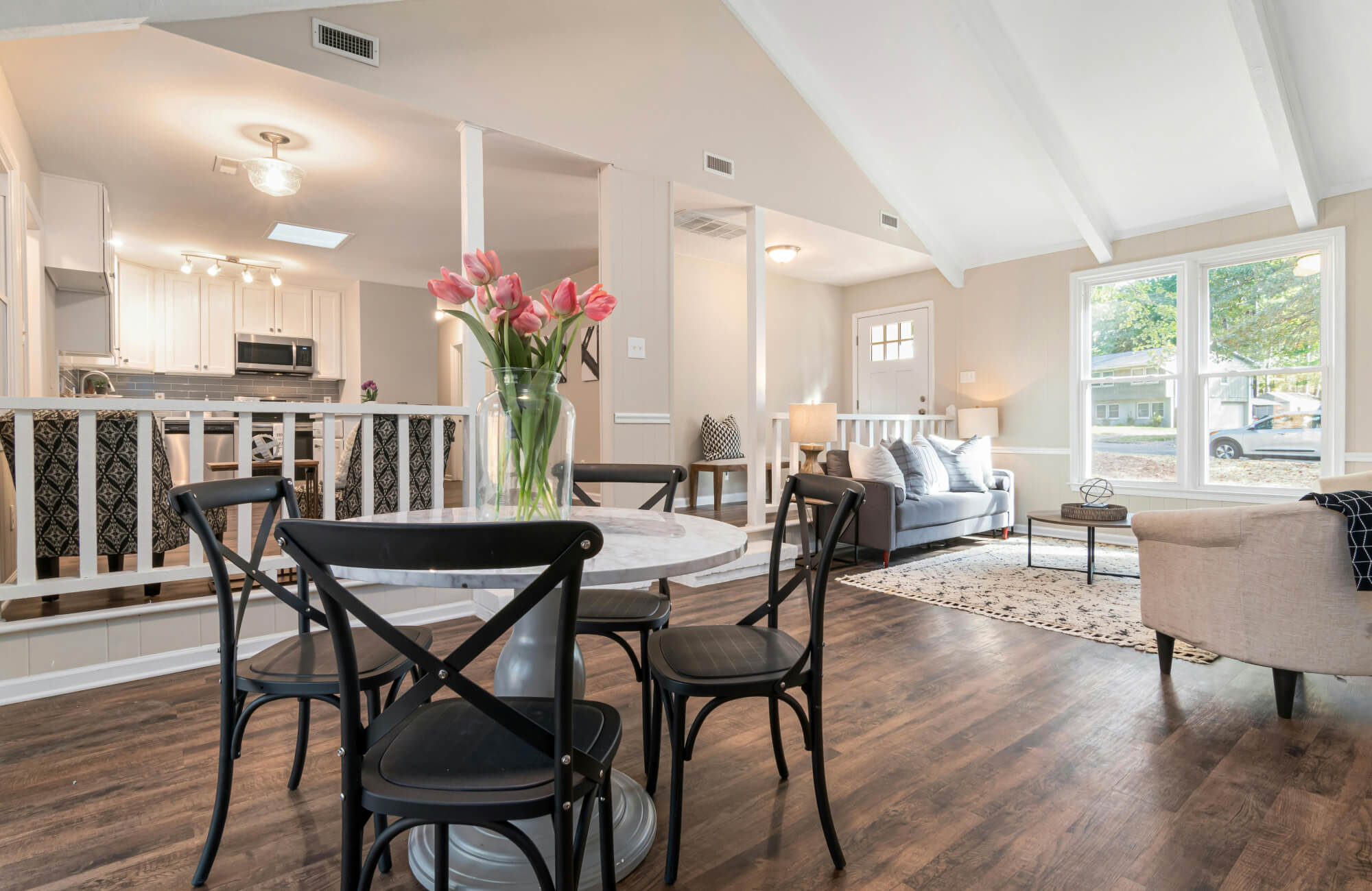 Casual open-concept layout featuring a marble dining table, mixed ceiling lights, and soft sunlight highlighting the living room and kitchen in one seamless space.