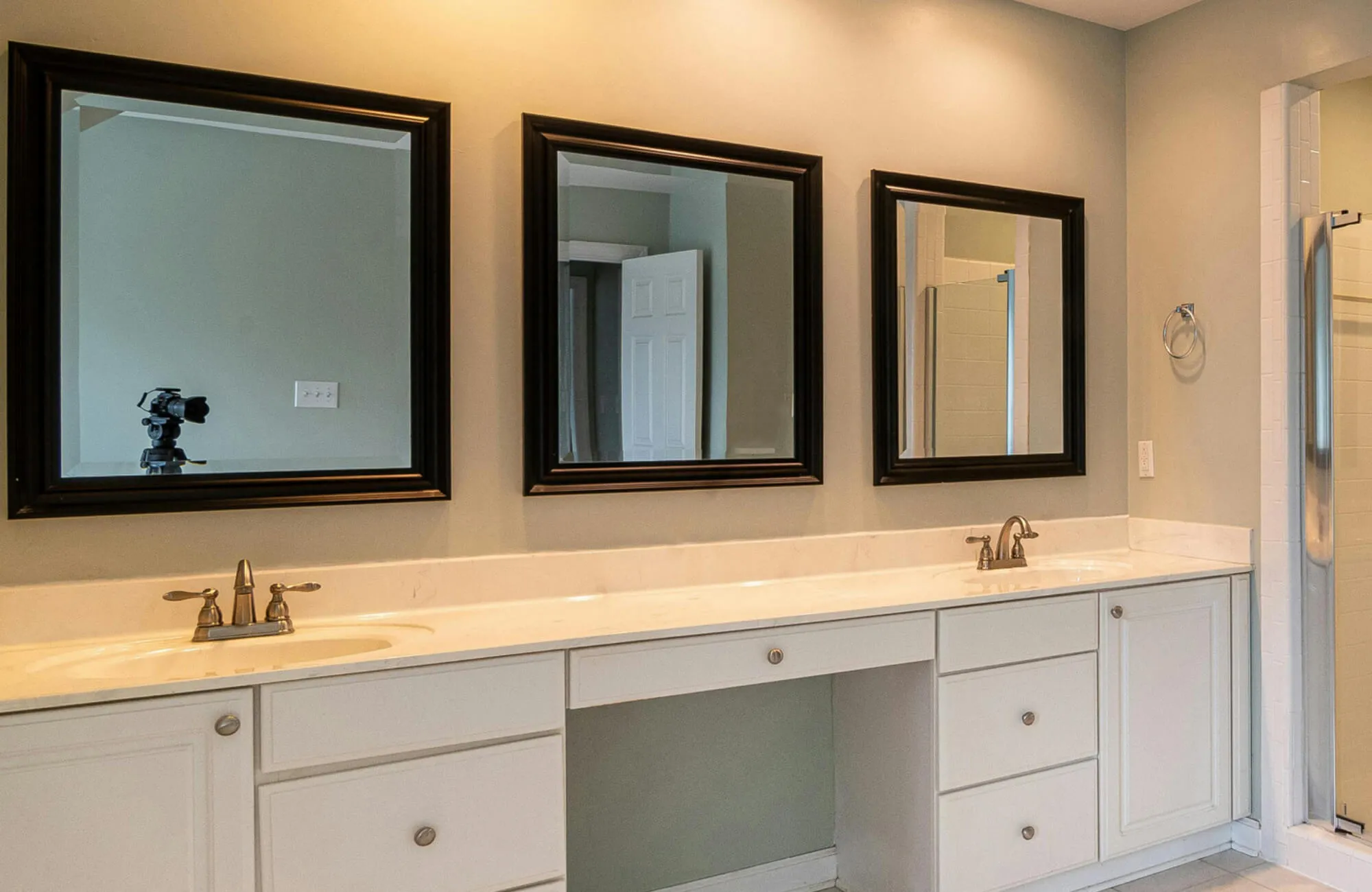 Dual-sink vanity with white cabinetry and black-framed mirrors in a modern bathroom setup.