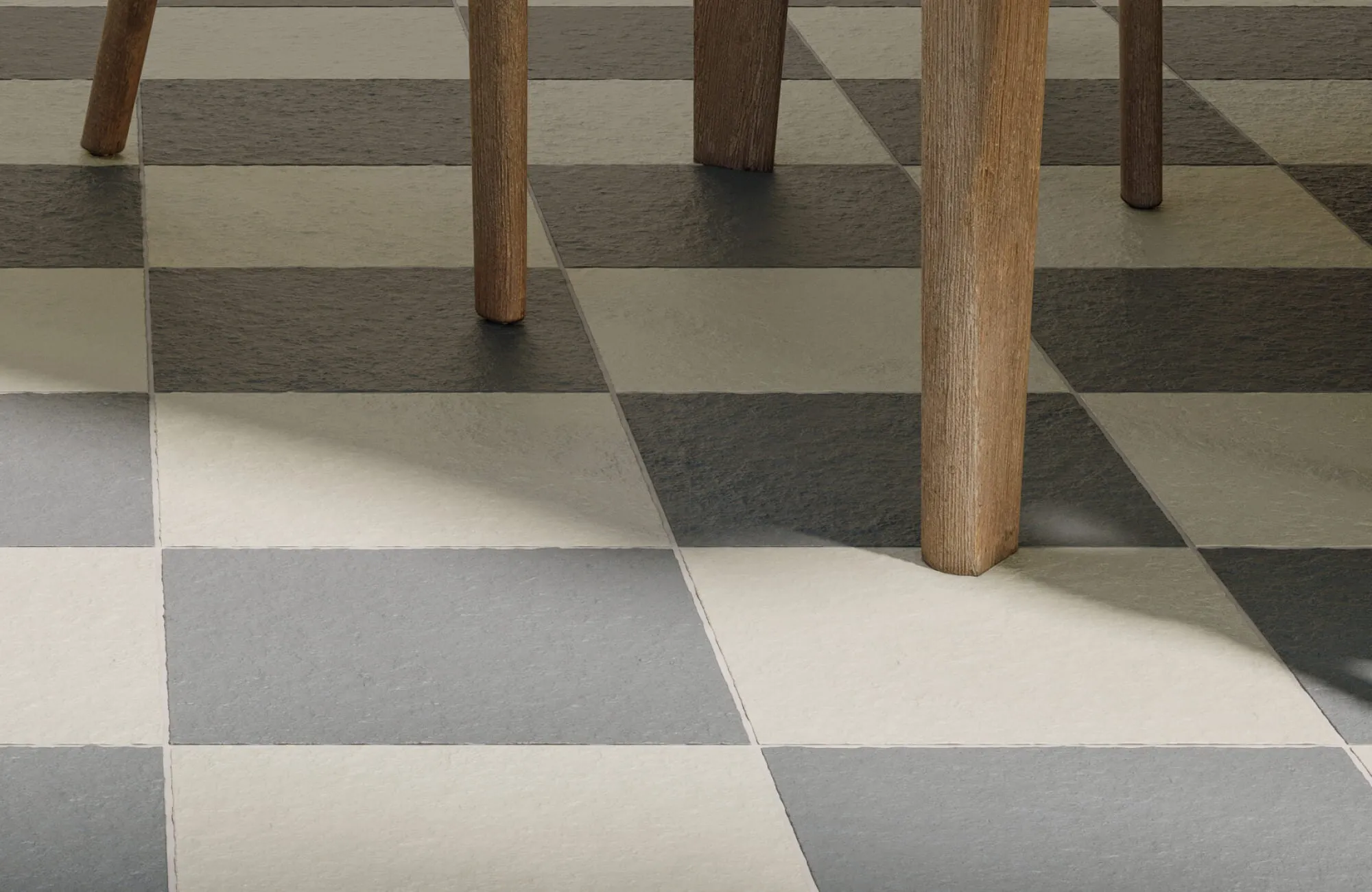 Classic checkerboard floor tiles in muted charcoal and cream tones, featuring a natural stone texture beneath wooden chair legs.