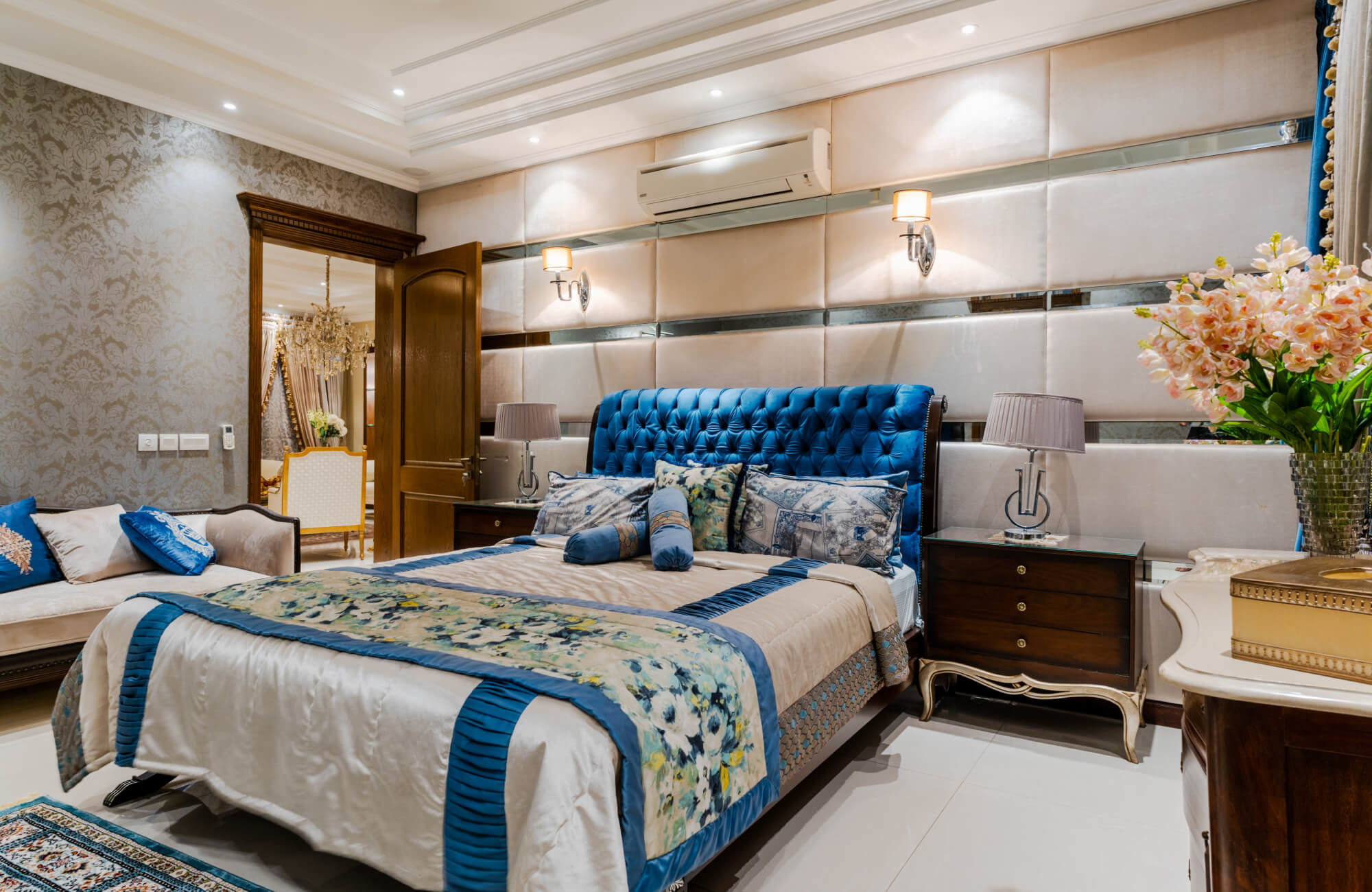 null Traditional bedroom with a blue tufted headboard, patterned bedding, layered pillows, and small blue bolster pillows styled near the center of the bed.