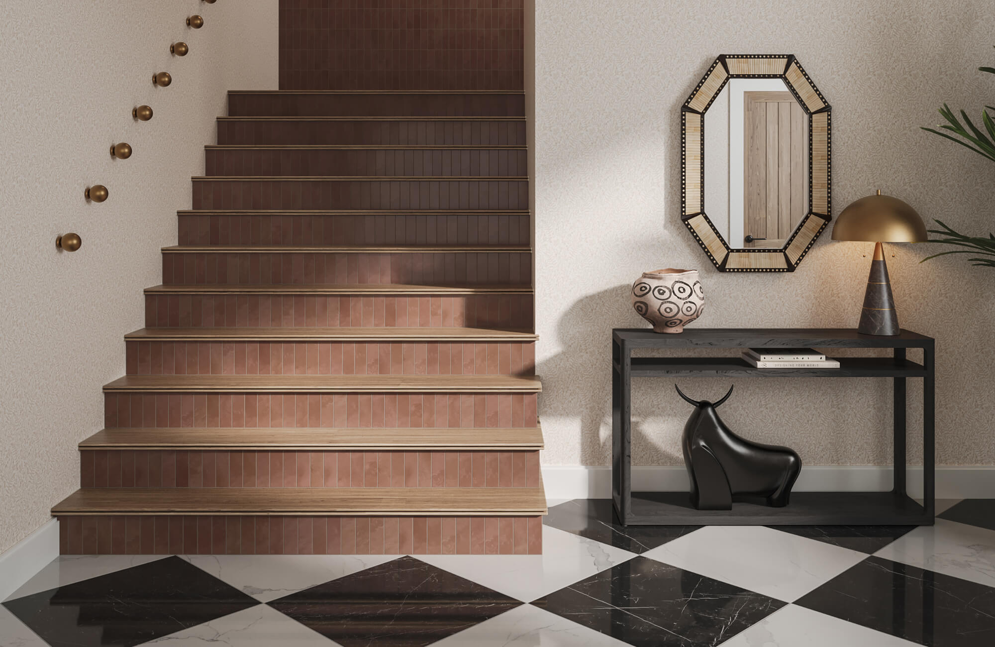 Entryway console with a patterned ceramic bowl, sculptural black accent, brass table lamp, and geometric mirror beside a tiled staircase.