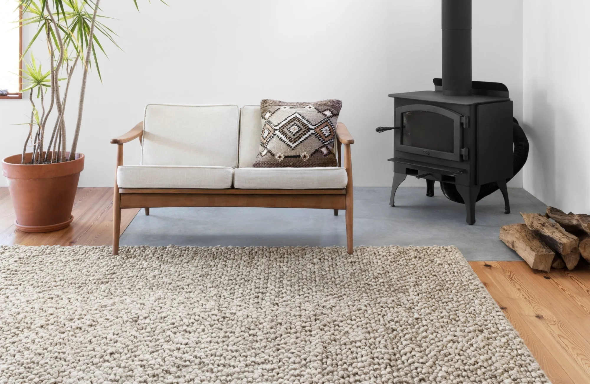 Cozy living space with a chunky wool rug, wooden furniture, and a fireplace, highlighting soft indoor textures.