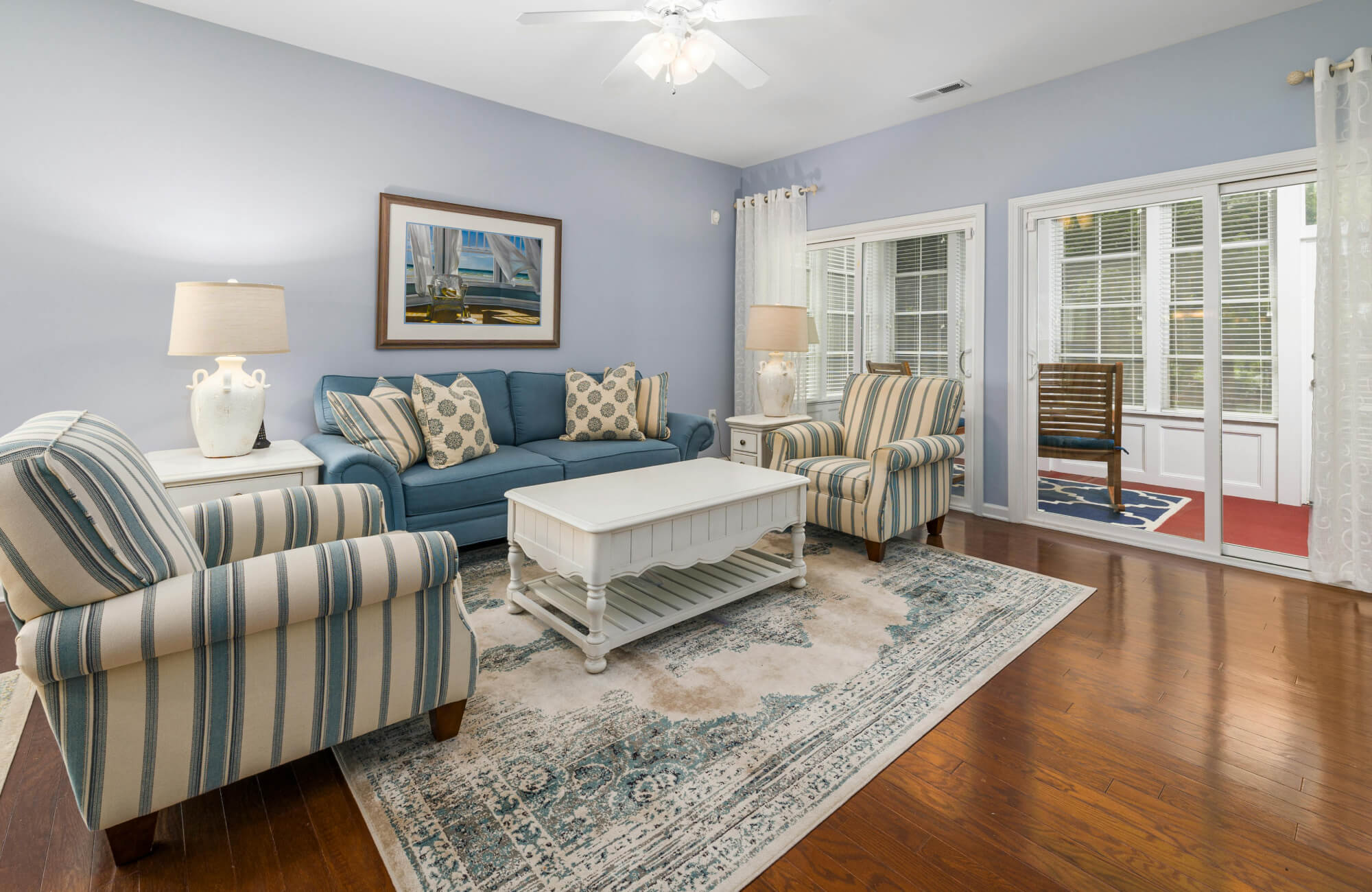 null Coastal-style living room with a blue and beige indoor rug transitioning to a navy rug in a sunroom.