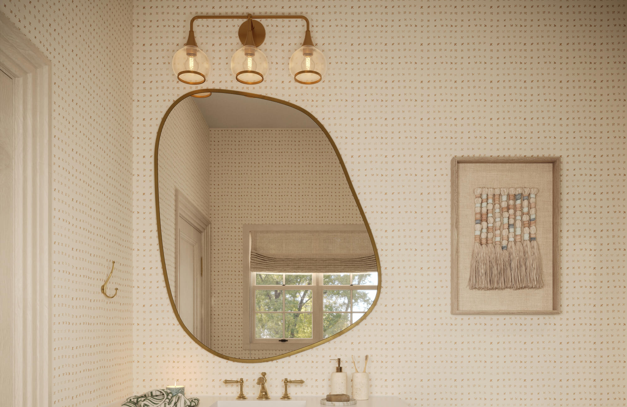 null Framed woven textile artwork styled beside an asymmetrical mirror above a green bathroom vanity with patterned wallpaper and warm brass lighting