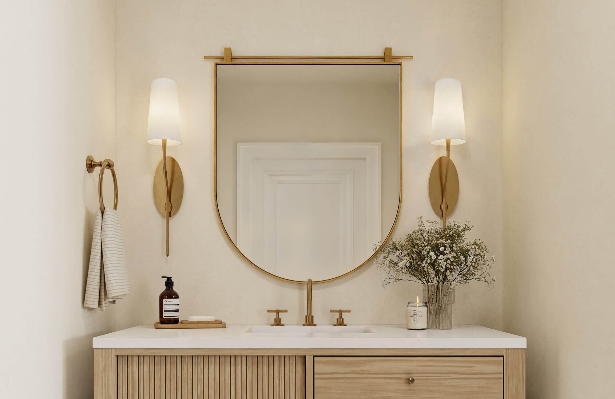 null Gold-framed mirror above a light wood double vanity, paired with gold wall sconces and neutral walls for a warm, minimalist bathroom look.