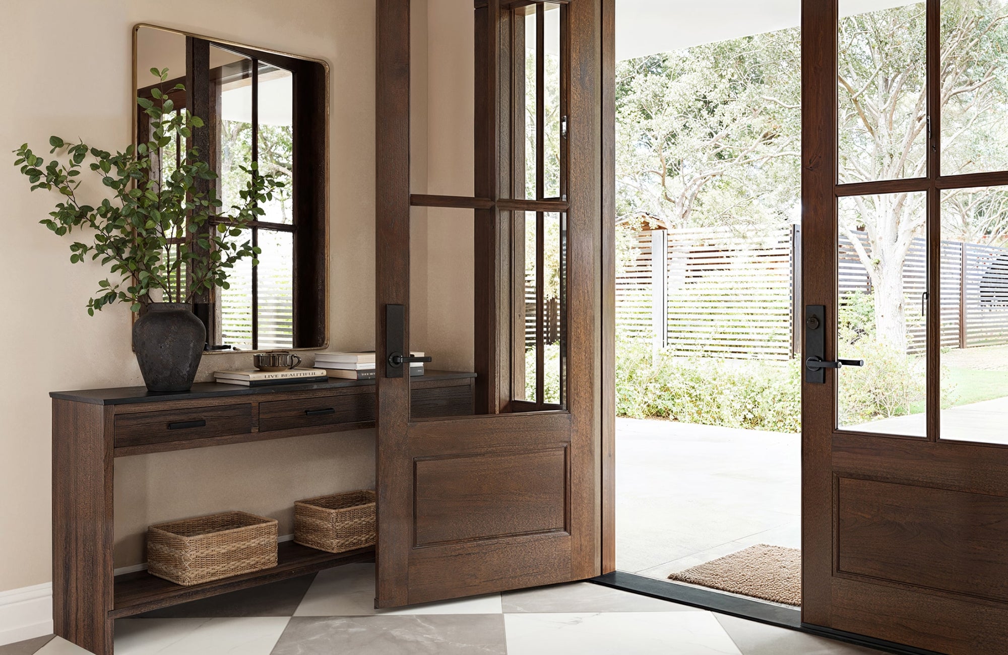 Entryway mirror reflecting natural light from glass doors, brightening the space and connecting indoors with outdoors.