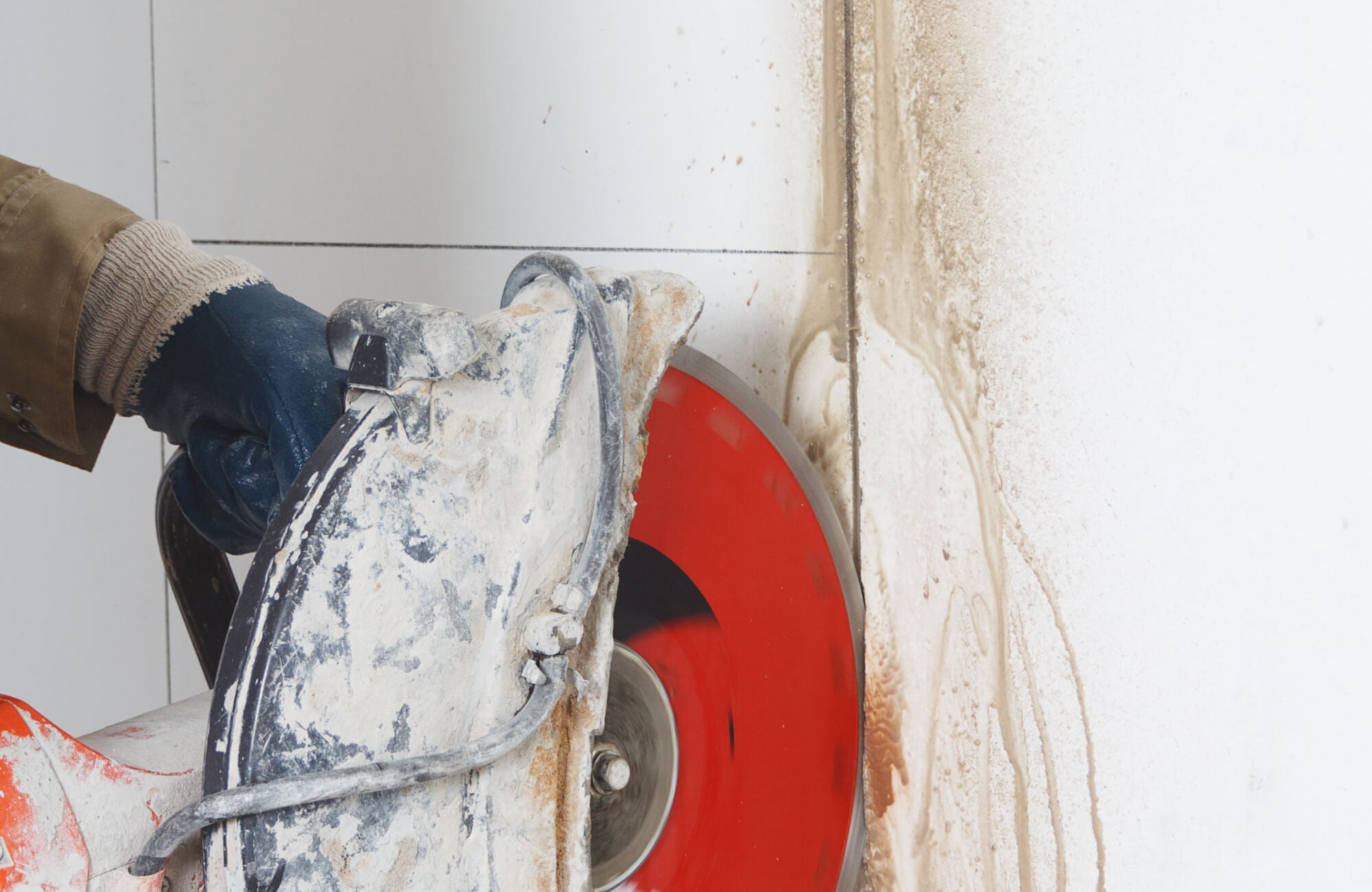 null Worker cutting into a tiled wall during bathroom demolition, removing old materials to start the remodel.