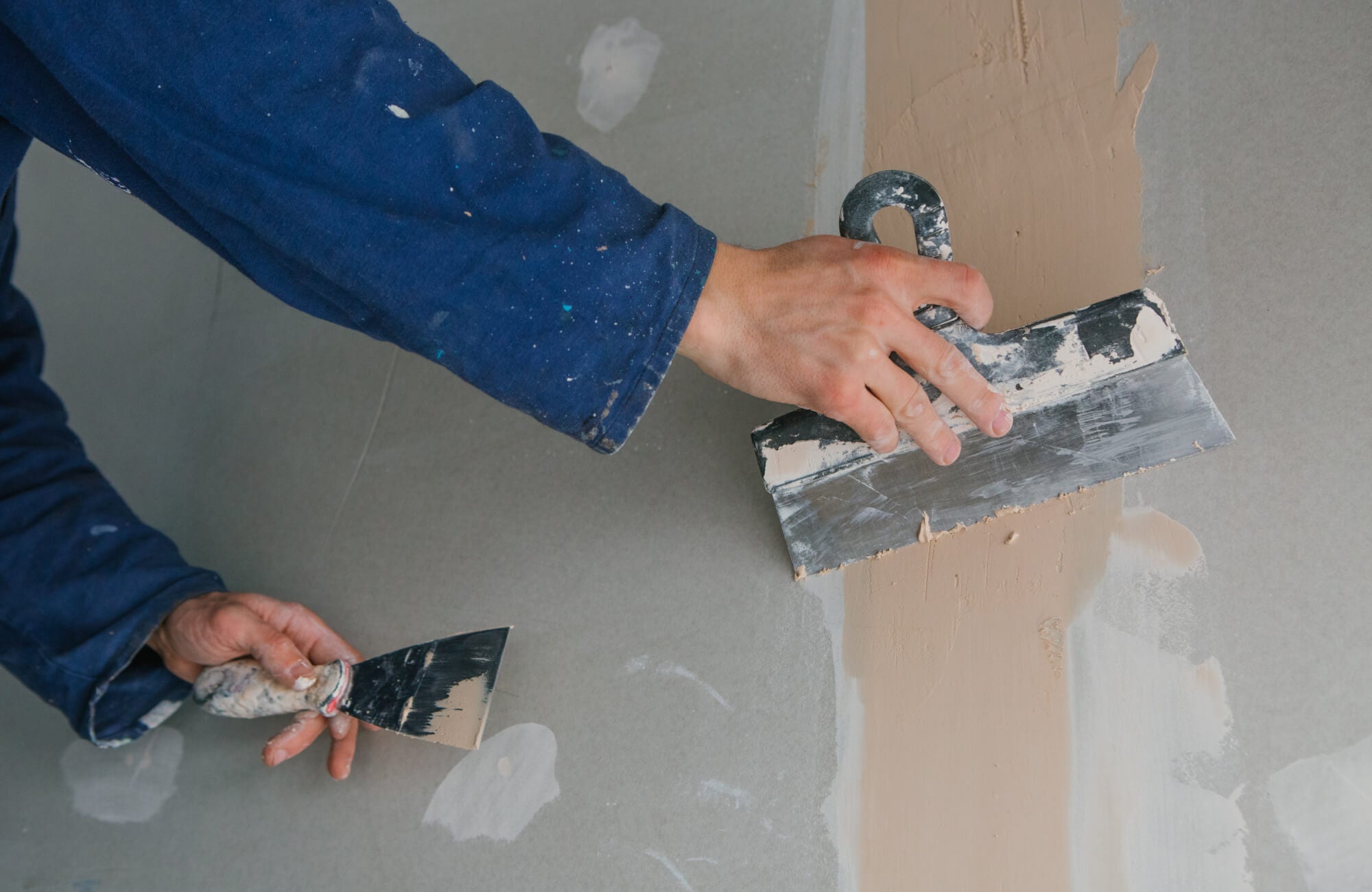 null Contractor smoothing wallboard seams to prepare bathroom walls for tile installation and finishing.