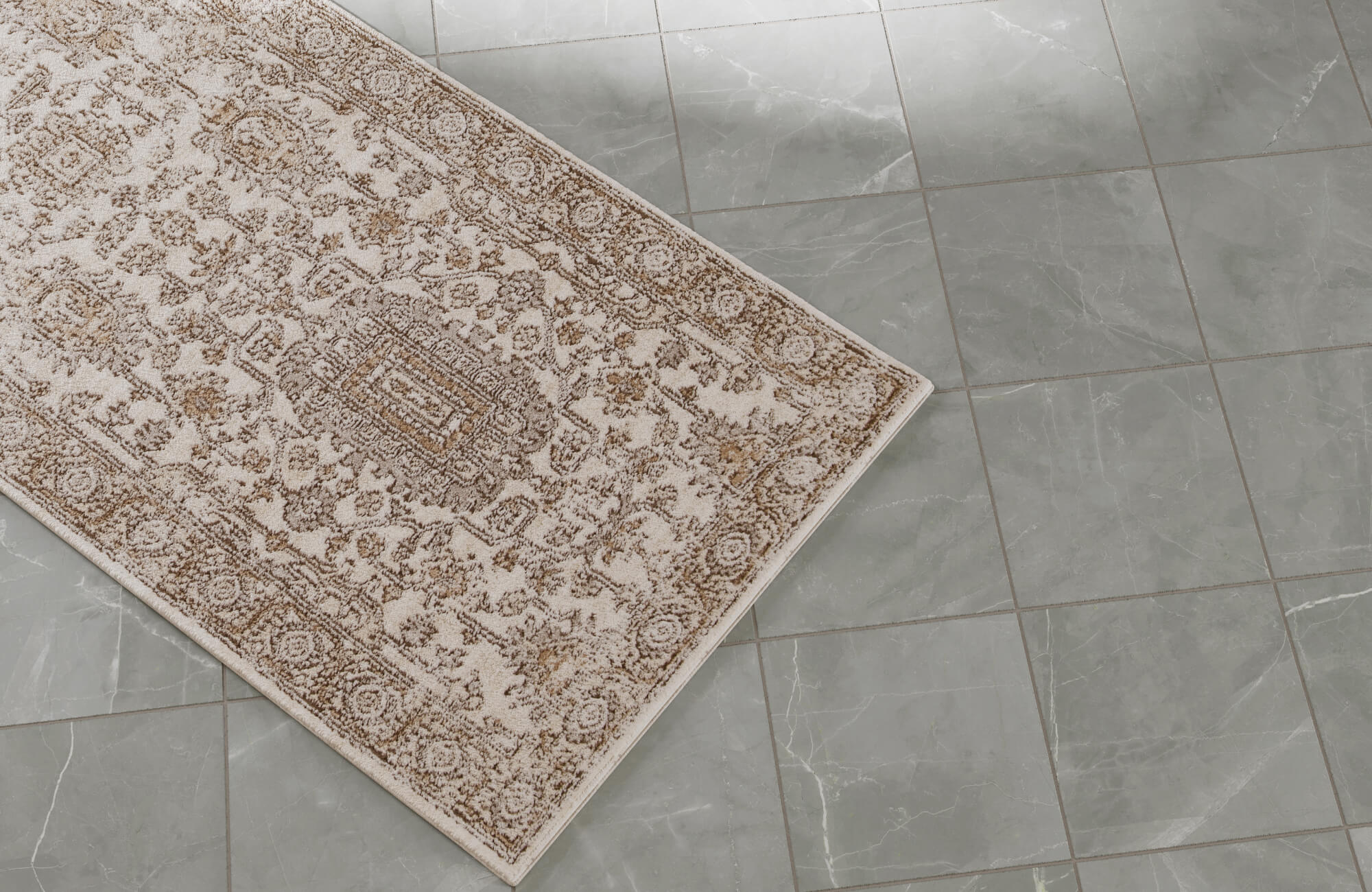 null A close-up of a beige patterned rug set against soft gray marble-look floor tiles with subtle veining.