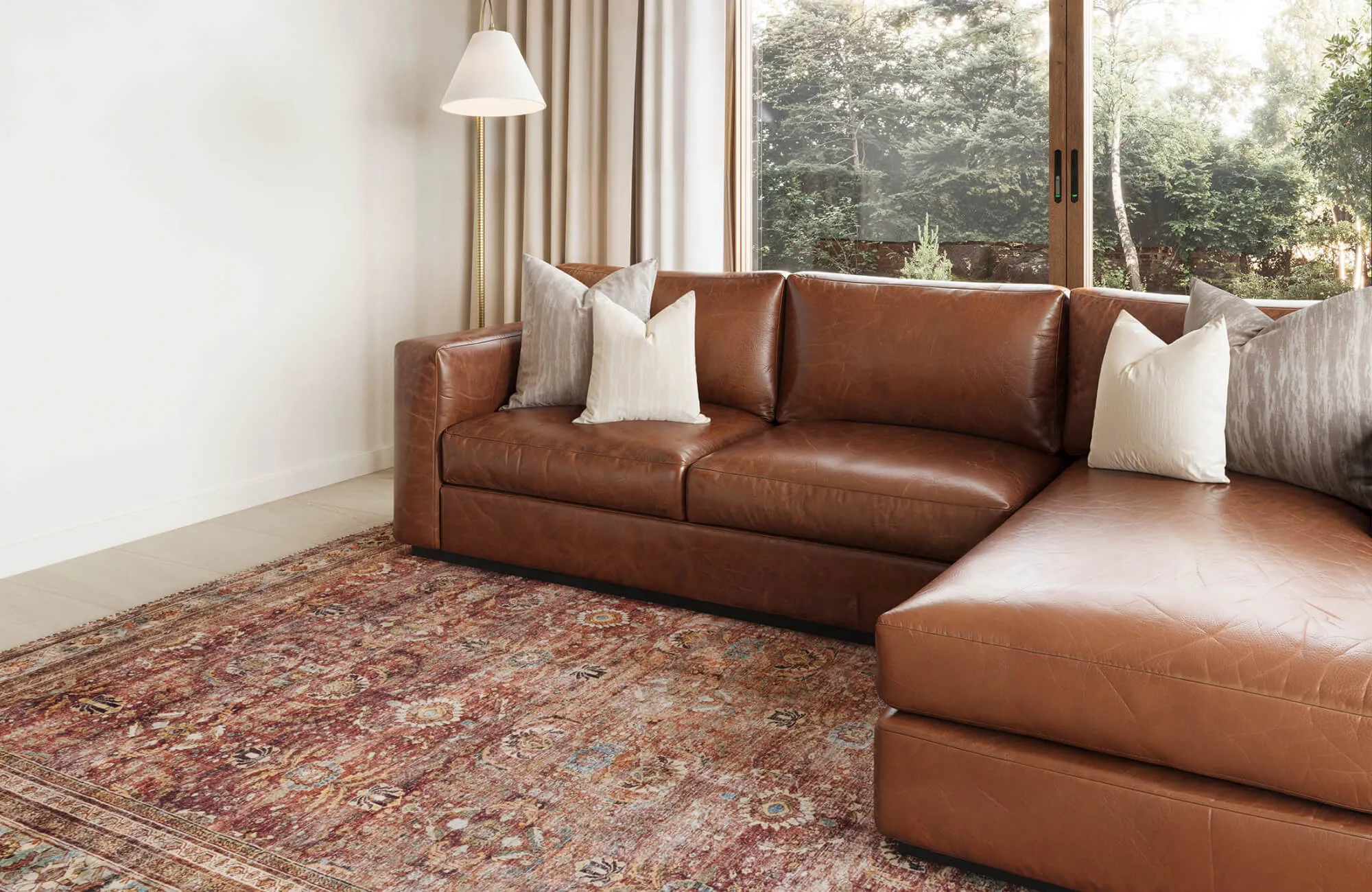 Warm and inviting living space featuring a rich brown leather sectional and a vintage-inspired 9x12 area rug in earthy tones.