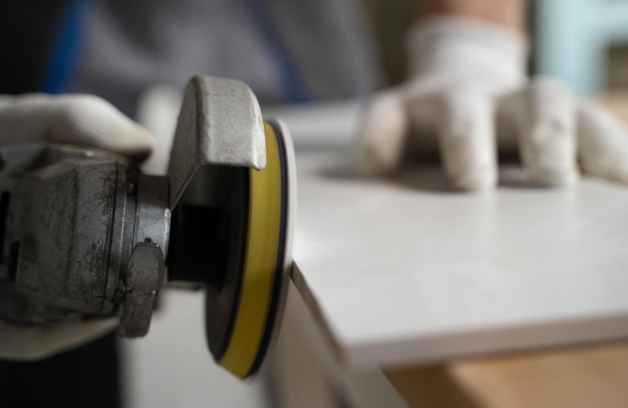 null Close-up of a worker polishing the edge of a checkered tile with a grinding tool, wearing protective gloves for precision.
