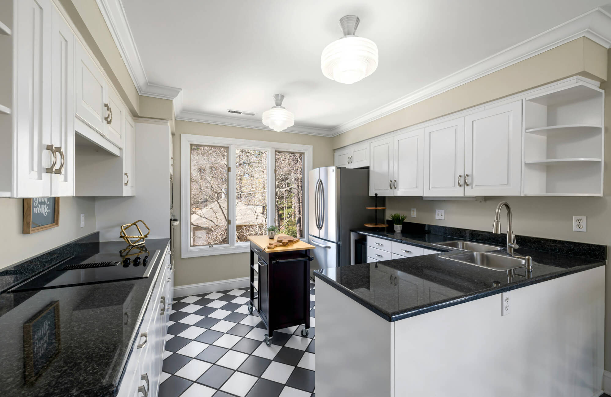 null Bright kitchen featuring black-and-white checkered floor tiles, white cabinetry, sleek black countertops, and stainless steel appliances.