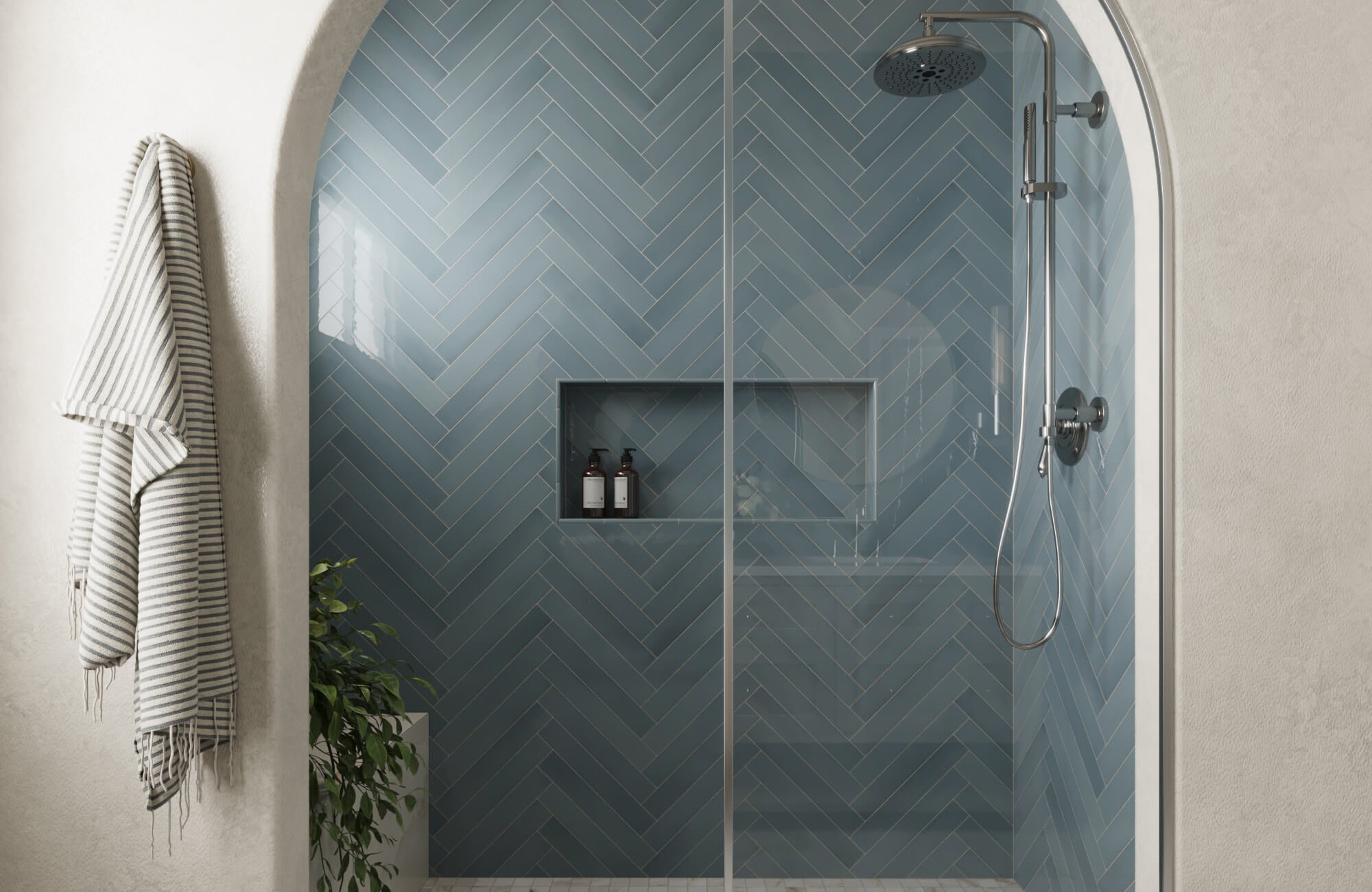 Modern walk-in shower with glossy blue tiles in a herringbone pattern, built-in niche shelving, and sleek chrome fixtures.