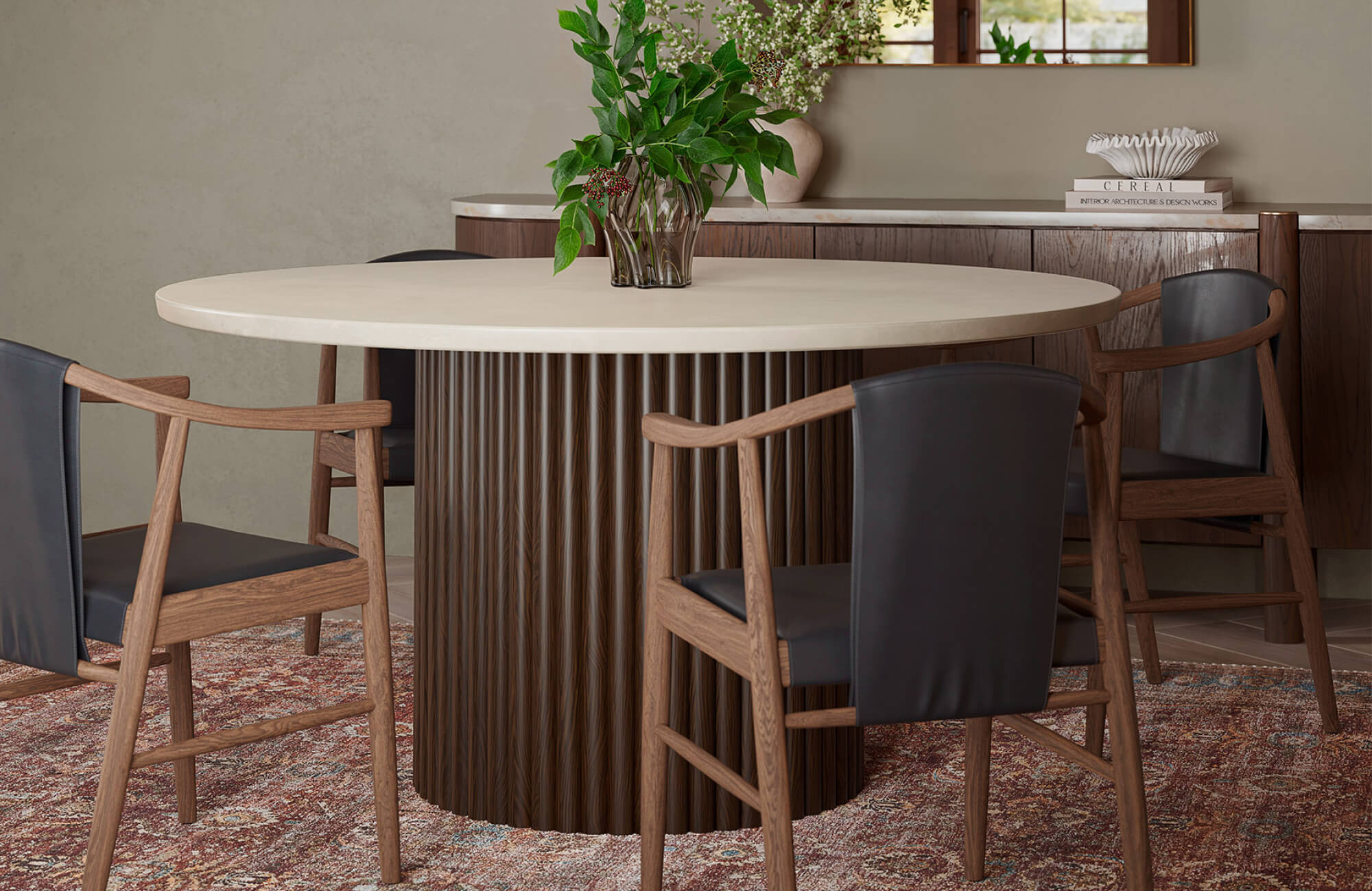 null A round cream marble dining table with a ribbed pedestal base styled with dark wood chairs and greenery.