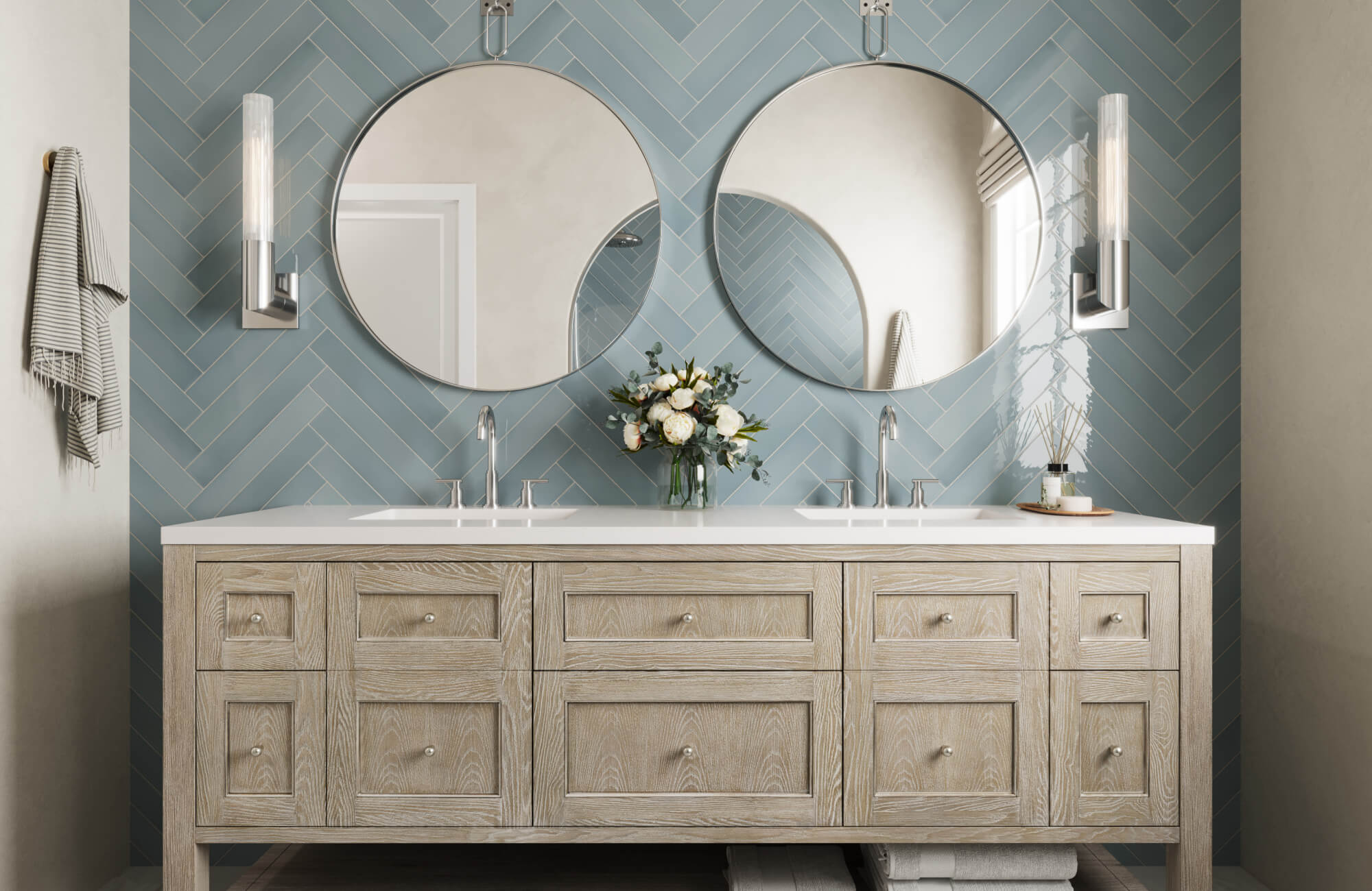 Modern double-sink vanity featuring circular mirrors and a soft blue herringbone wall tile that adds texture and balance to the space.