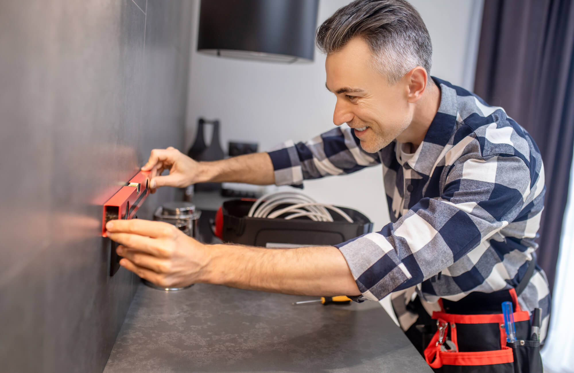 Professional installer using a leveling tool to align tiles on a wall, ensuring a precise and even layout.