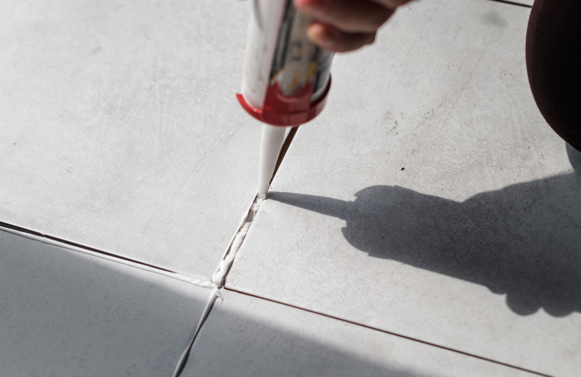 Worker sealing tile joints with caulk, highlighting attention to detail and proper tile installation technique.