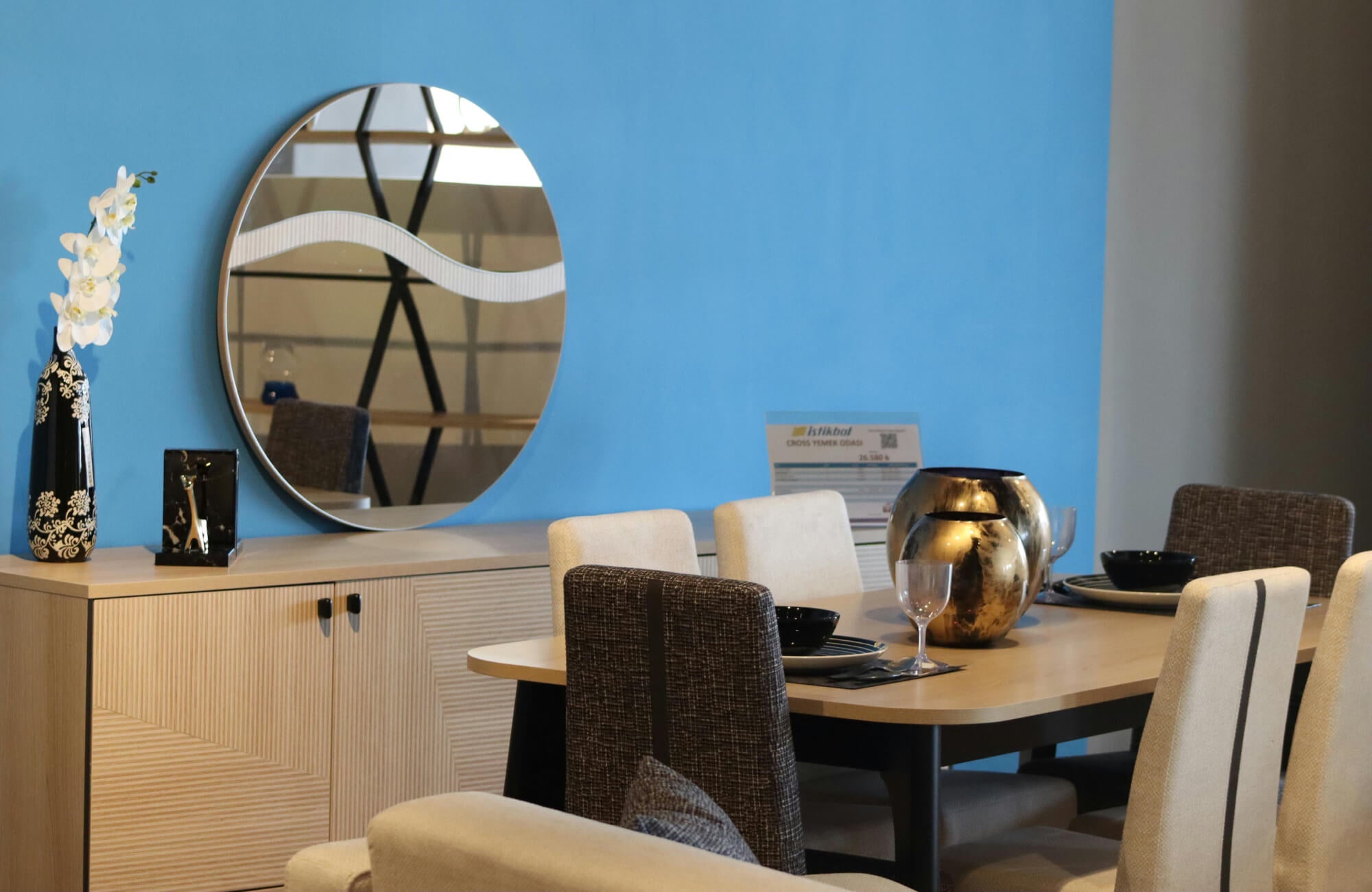 Round mirror on blue wall reflecting modern dining table and neutral seating