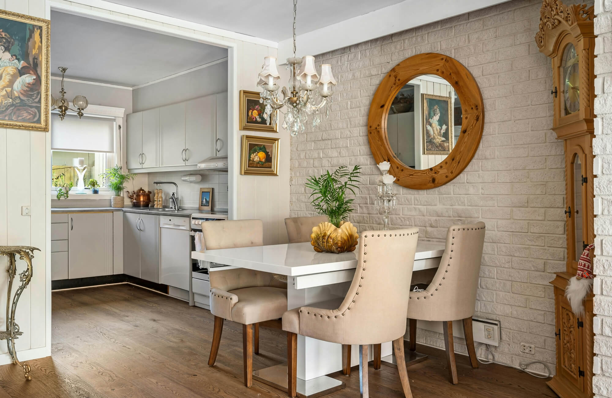 Round wooden-framed mirror reflecting cozy dining nook beside the kitchen