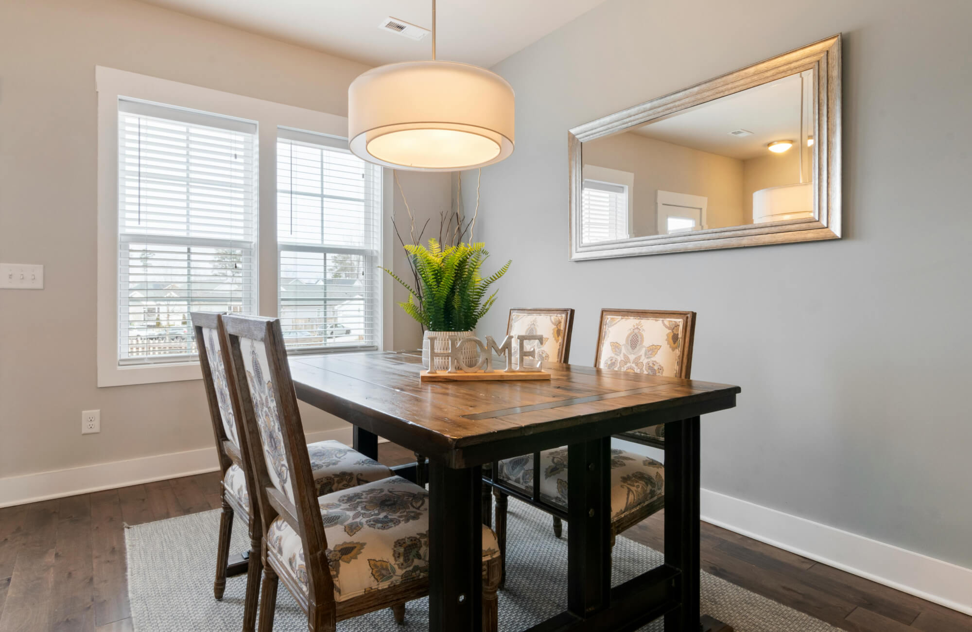 Silver-framed mirror reflecting rustic dining table and soft neutral décor