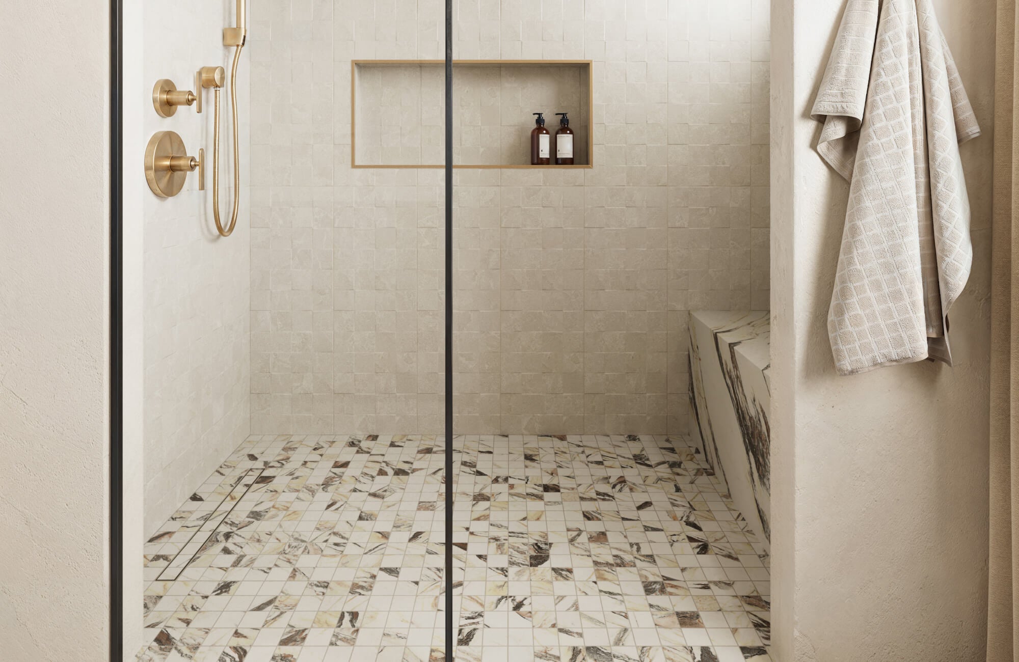 null Walk-in shower with cream mosaic tile walls, patterned marble floor, brass fixtures, glass divider and built-in niche.