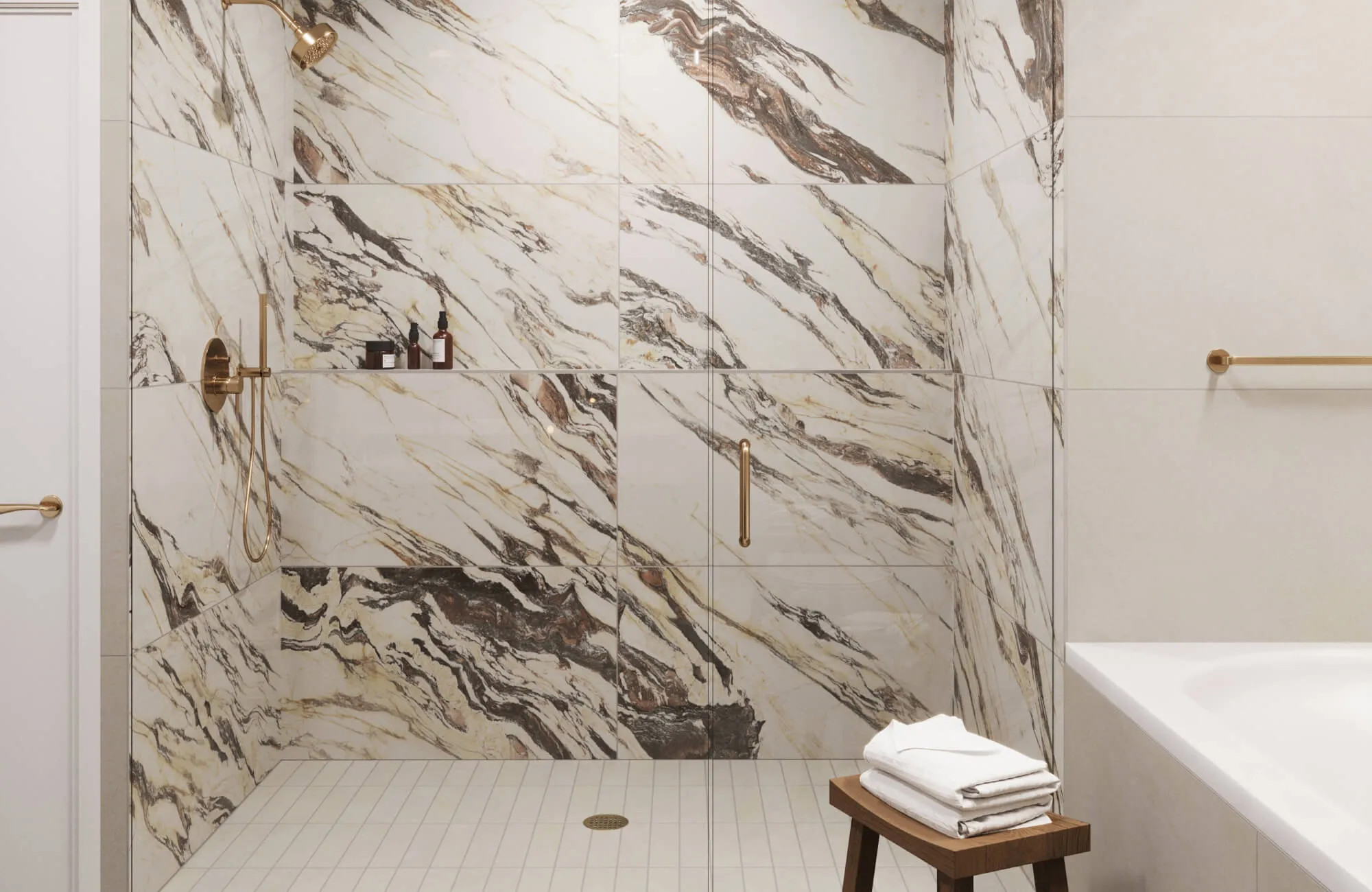 Bathroom shower clad in white and beige marble look tiles with dramatic brown veining, paired with gold-toned hardware.