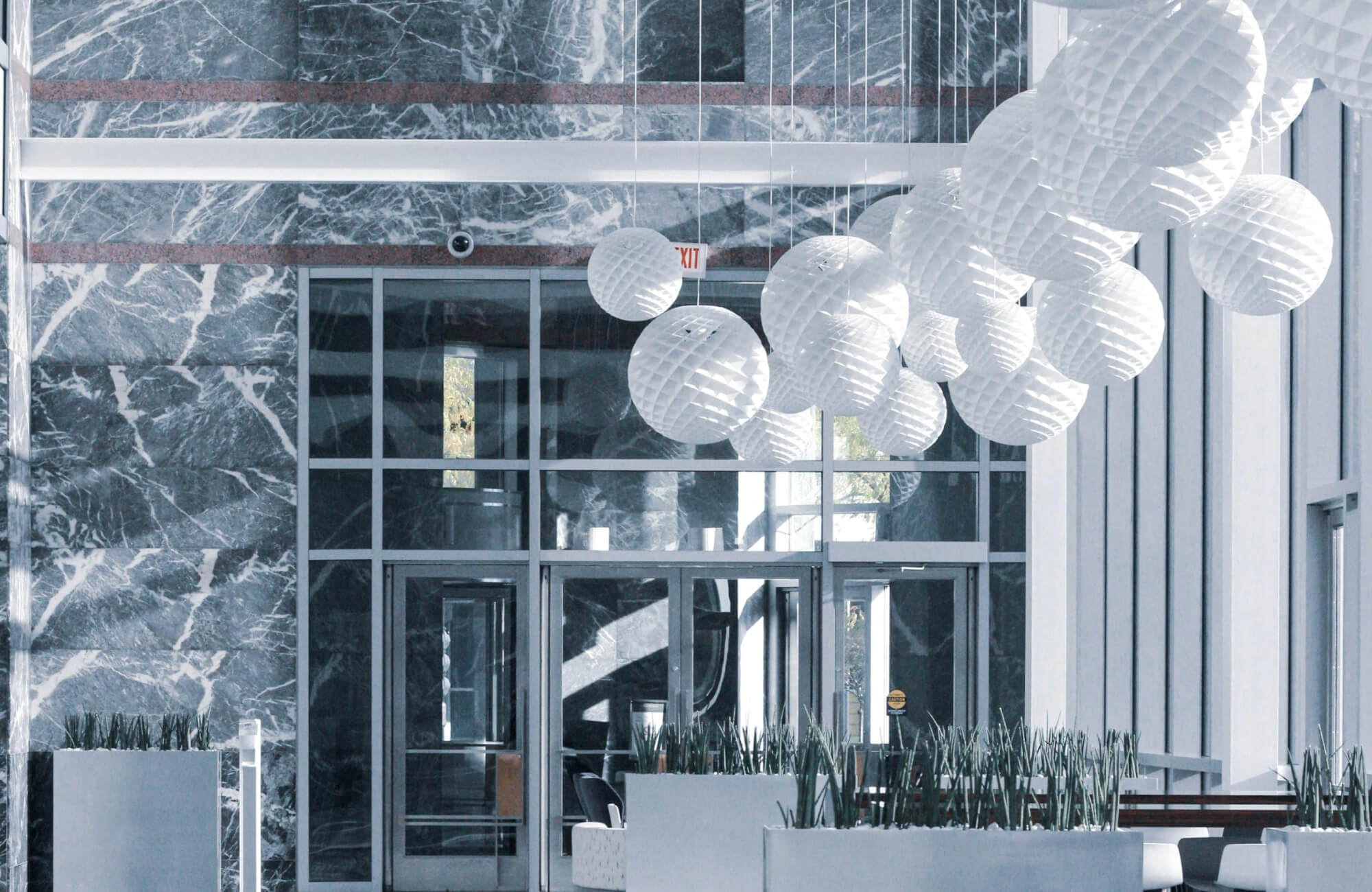 null A modern lobby with striking gray marble walls, floor-to-ceiling windows, and sculptural white paper lanterns creating a bold yet airy ambiance.