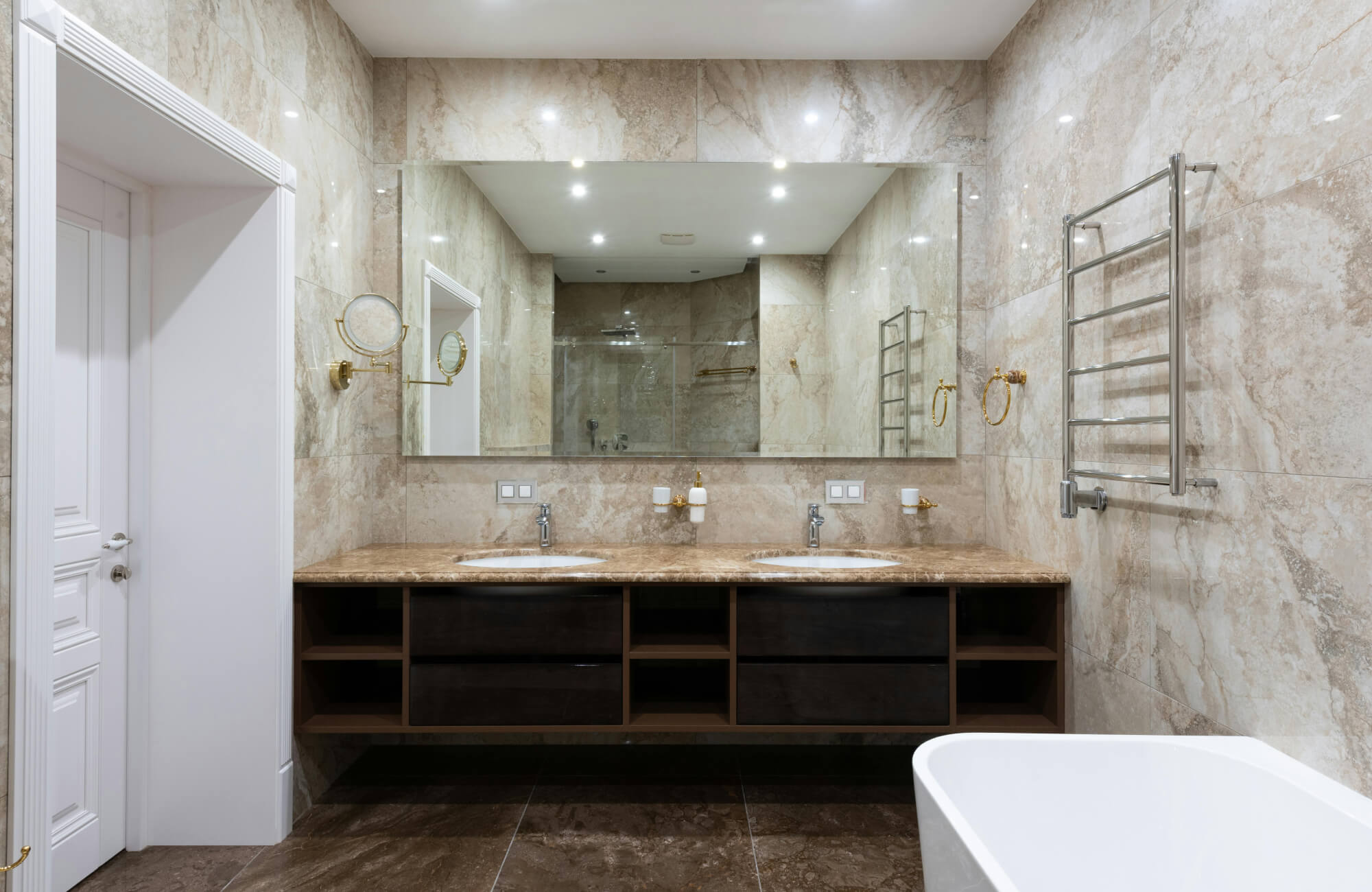 null A luxurious bathroom with floor-to-ceiling beige marble tiles, a double vanity with a rich stone countertop, and gold-accented fixtures for an elegant touch.