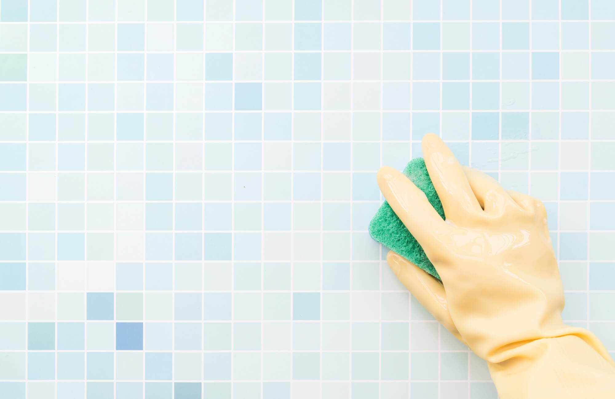 null Close-up of hand cleaning glossy zellige-style tiles, showing the reflective surface and subtle color variation.