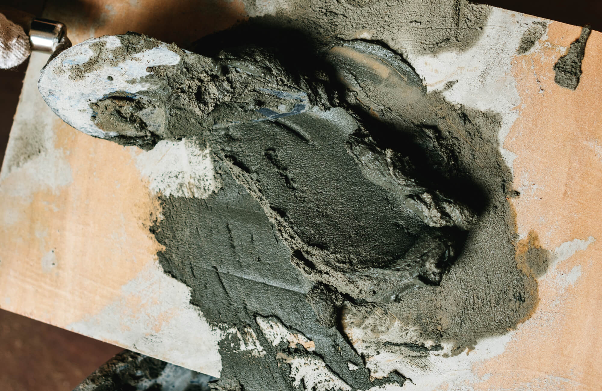 Fresh mortar being spread with a trowel for a mosaic tile surface, ready for tile installation.