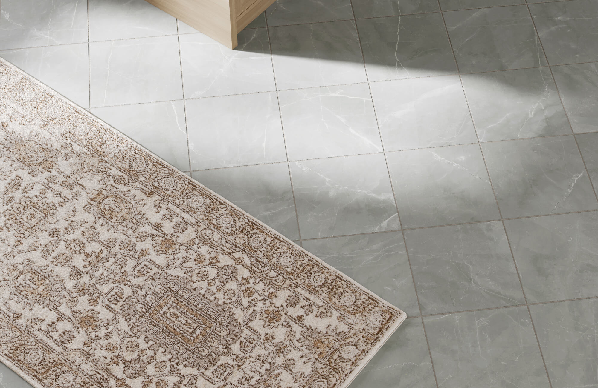 Close-up of patterned polypropylene rug edge on gray tiled floor, highlighting intricate design and low-pile construction detail.