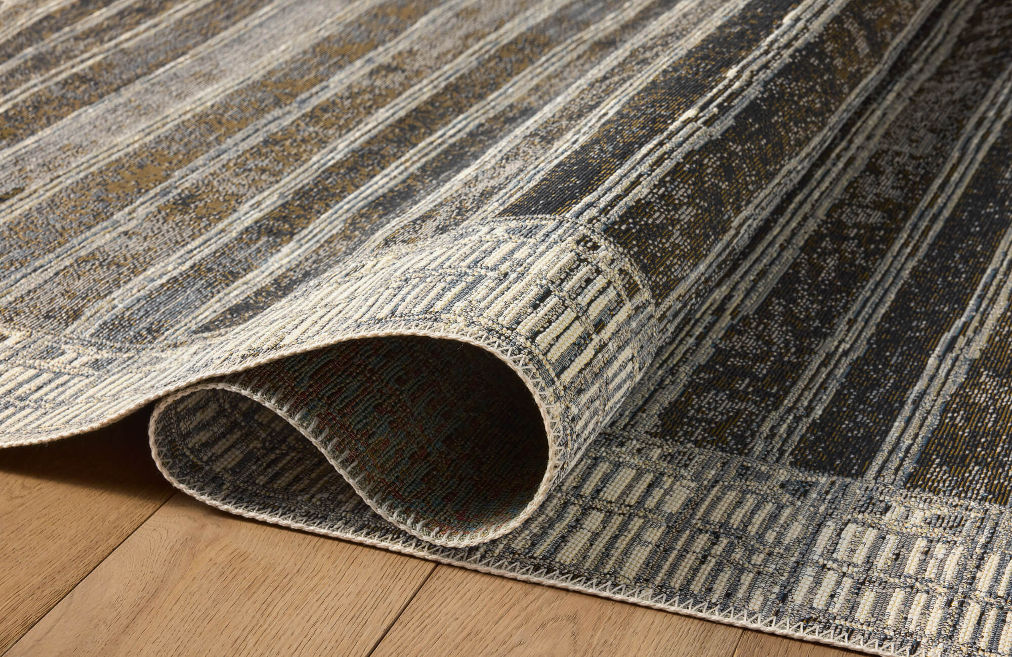 Folded polypropylene rug showing textured weave and flexible backing, with detailed pattern and durable stitched edges.