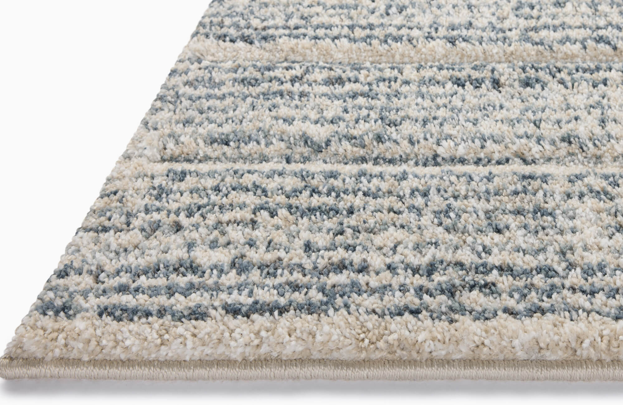 Plush loop polypropylene rug with a soft striated pattern in muted blue and beige tones, creating a cozy, modern aesthetic.