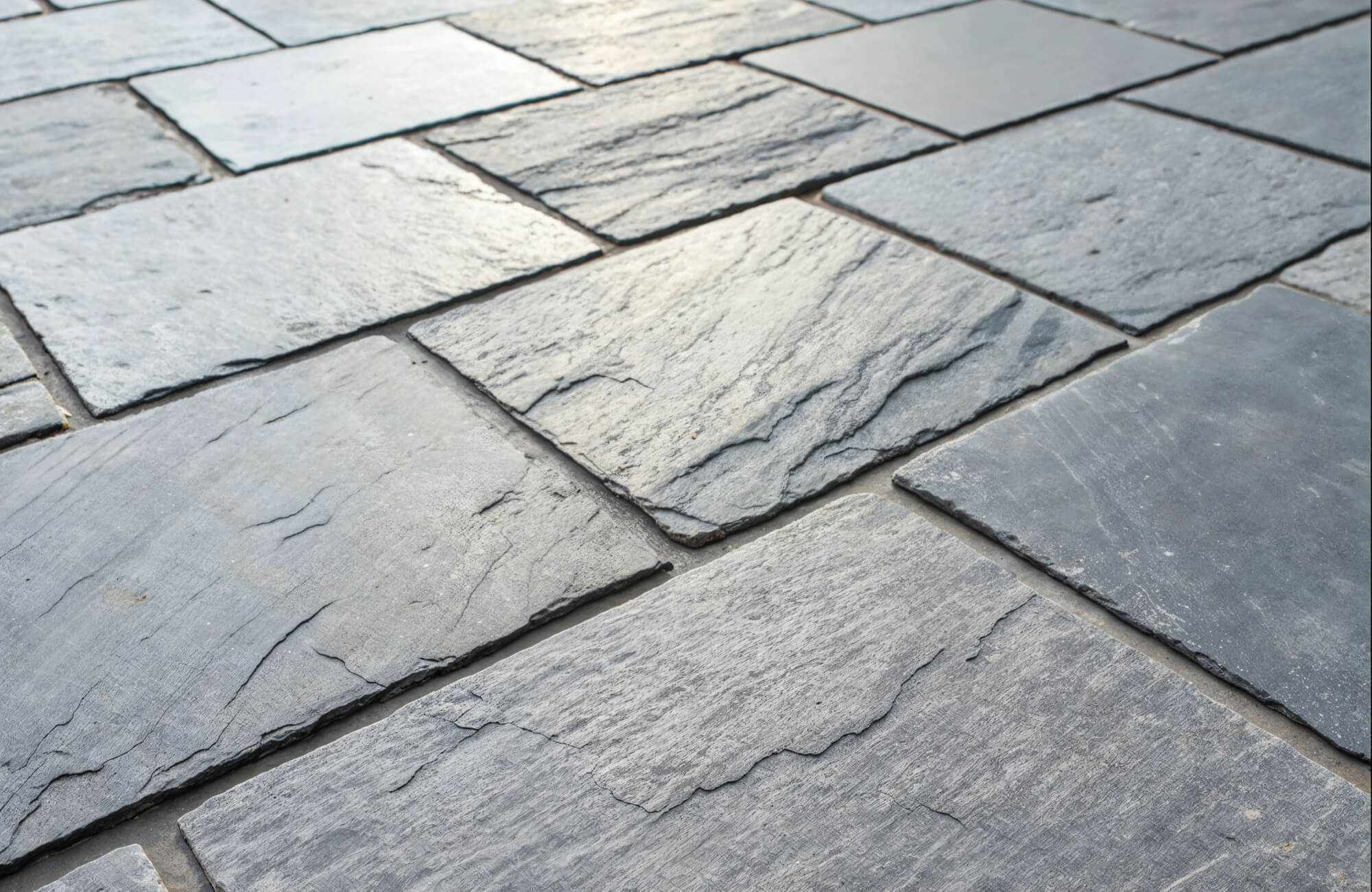 Gray slate floor tiles with natural variation and layered texture, arranged in a staggered pattern that highlights the stone’s organic surface.