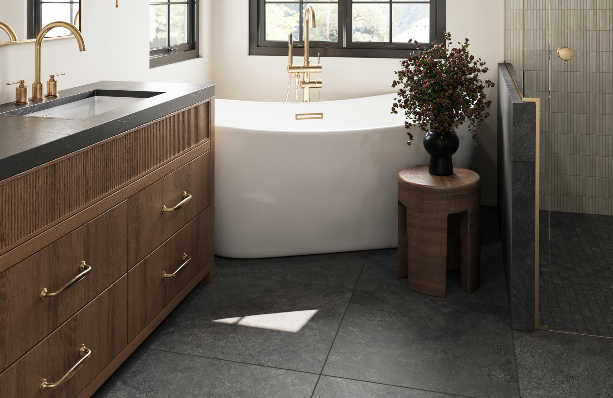 Dark slate-look floor tiles paired with a freestanding soaking tub and warm wood cabinetry, highlighting a balanced, moisture-friendly surface suited for bathrooms.