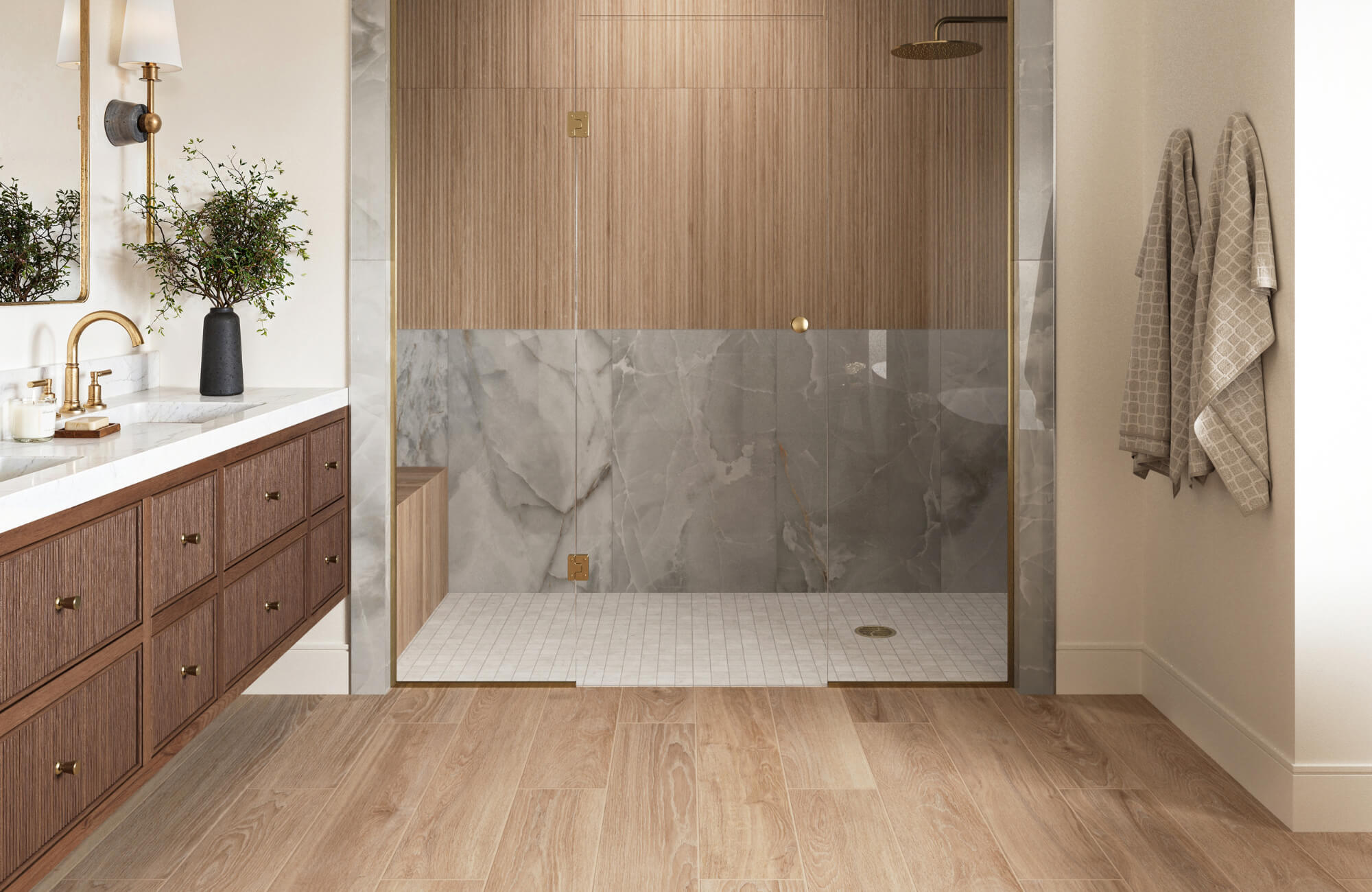 Bathroom with wood look tile flooring, marble look shower walls, vertical wood accent tiles, and a vanity with brass fixtures.