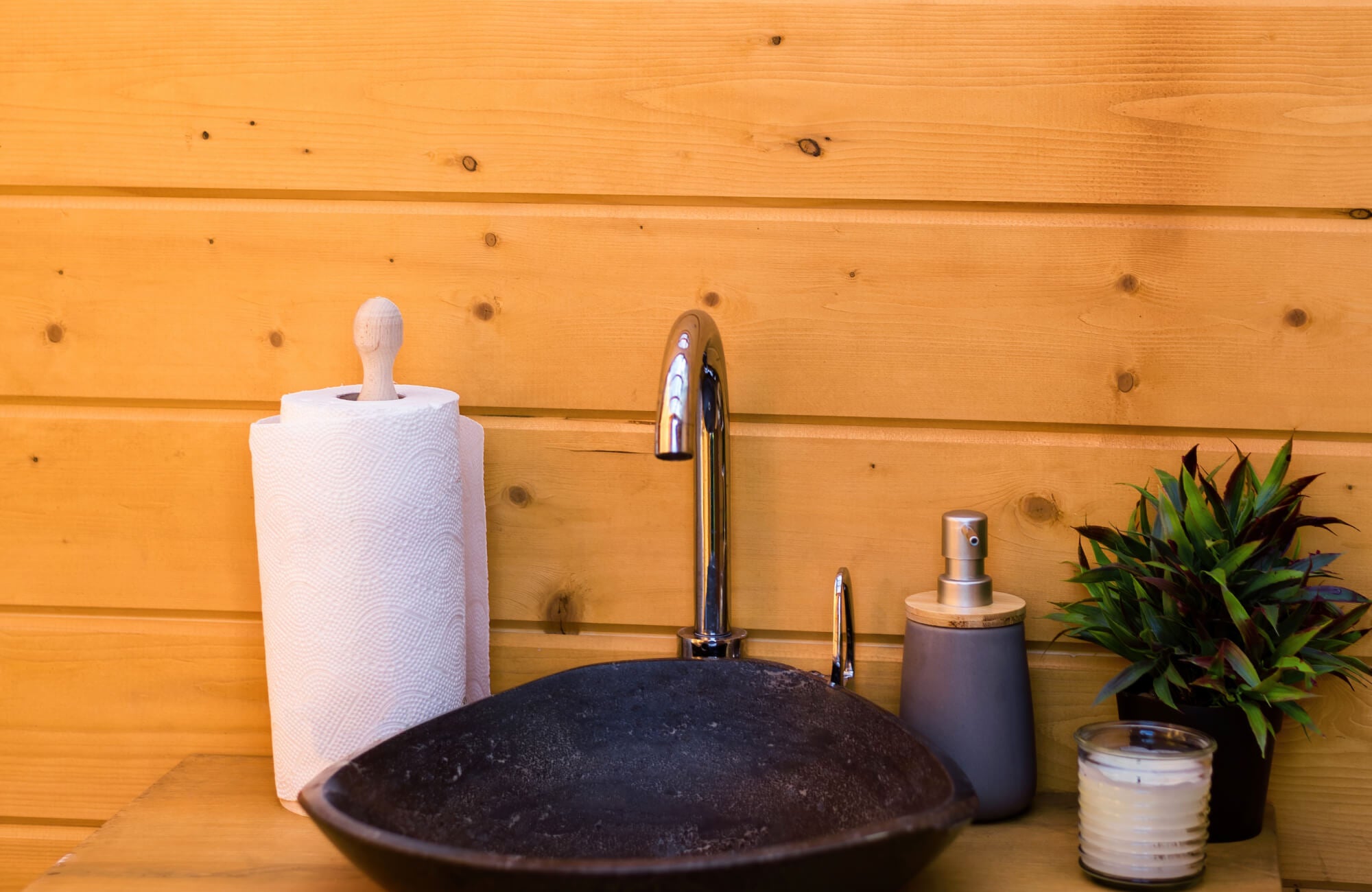 null Modern bathroom detail with polished wood walls, a black vessel sink, and minimalist decor, exuding natural elegance and simplicity.