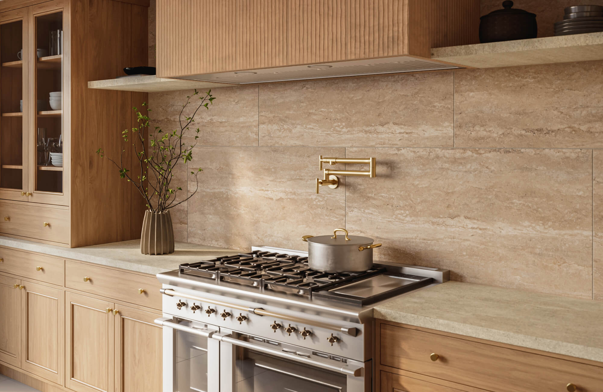 null Warm contemporary kitchen with large-format travertine tile backsplash, light wood cabinetry, stone countertops, and a stainless steel range with brass pot filler.
