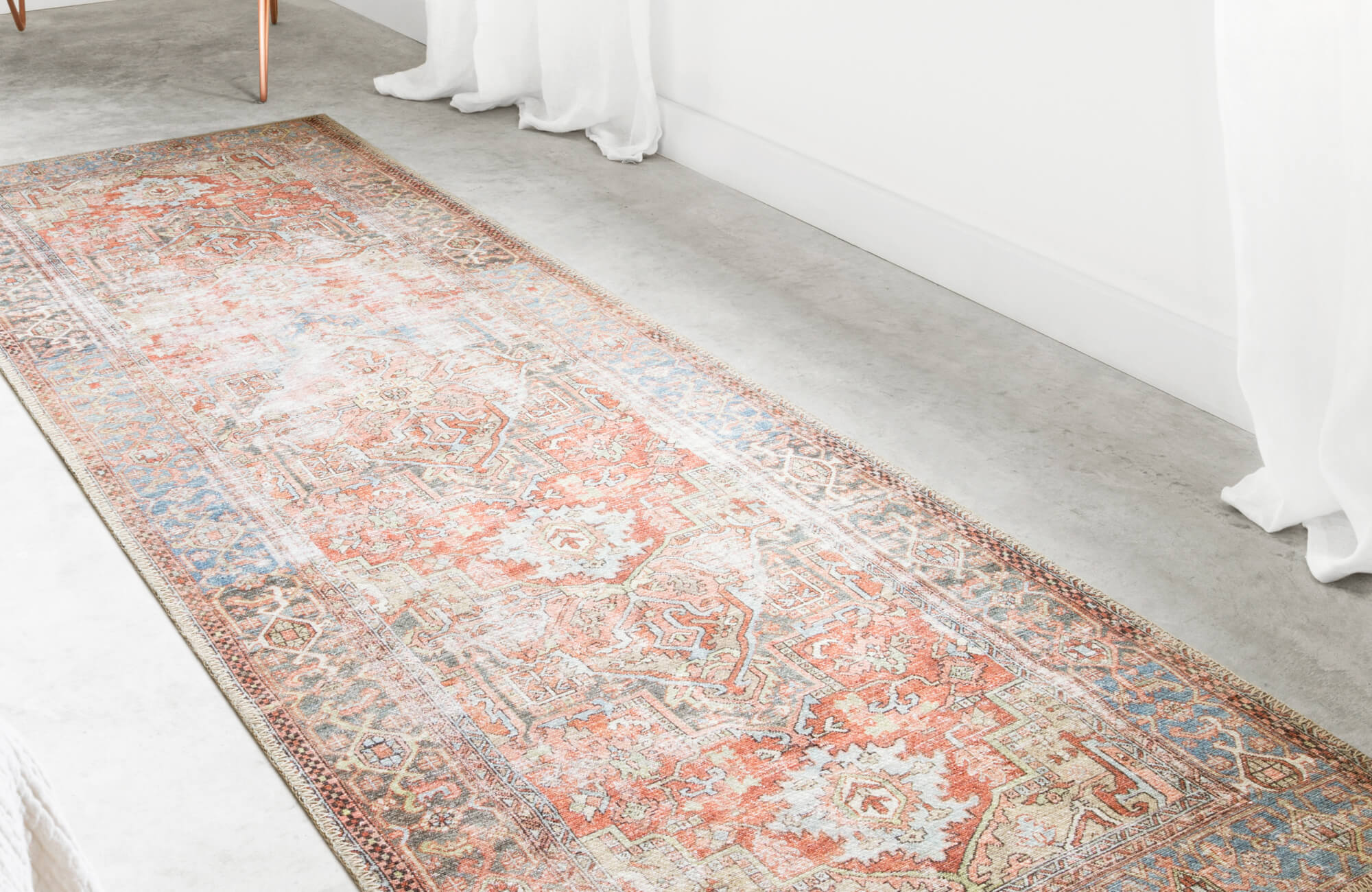 Runner rug in soft orange tones on light concrete floor, demonstrating how light rugs add brightness and space in narrow, small areas