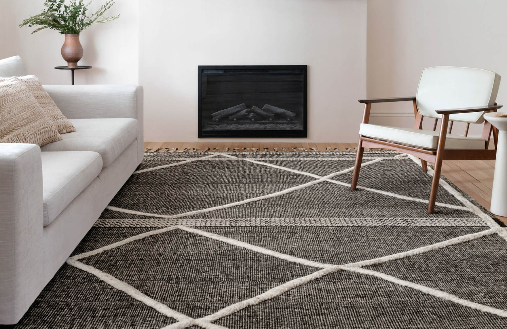 Living room with a dark geometric rug under light furniture, showing how dark rugs add contrast and coziness in compact spaces