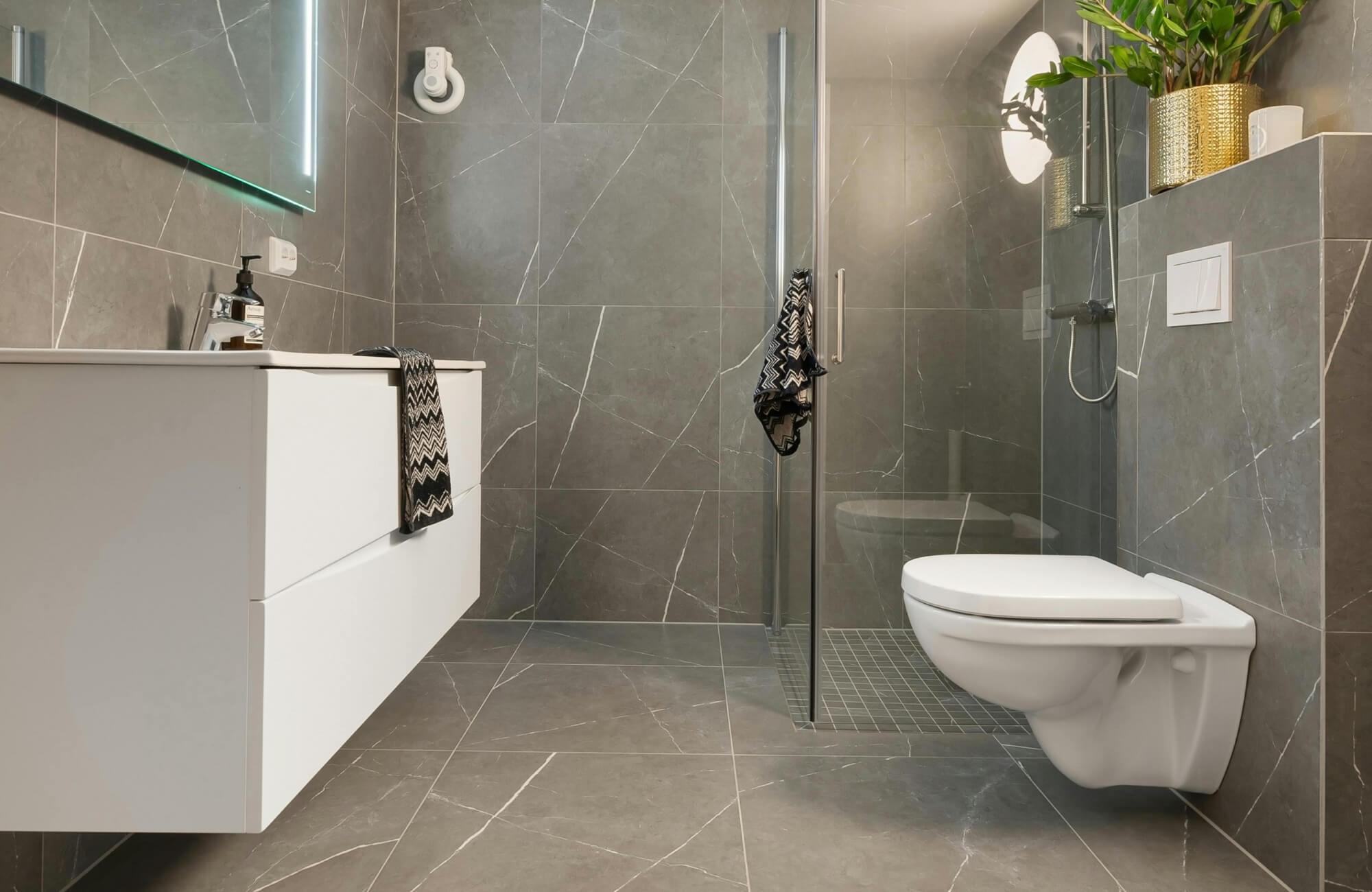 null Modern bathroom showcasing large-format modern bathroom tile in a matte gray stone look with subtle veining, complemented by a floating white vanity, wall-mounted toilet, frameless glass shower, and soft integrated lighting for a clean, contemporary feel.